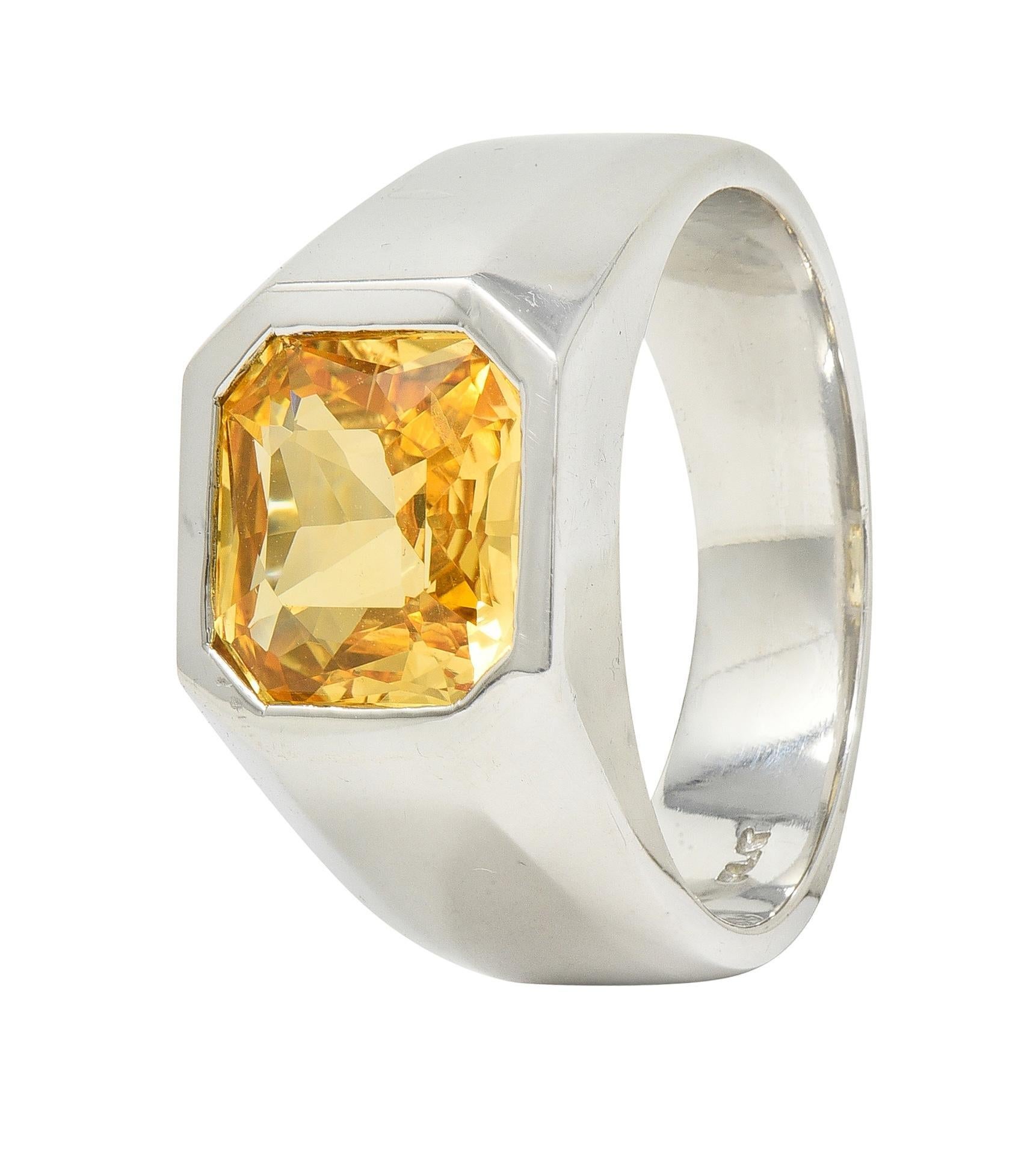 Centering a cushion cut sapphire weighing 4.02 carats total - transparent orangy-yellow in color
Natural Sri Lankan in origin with no indications of heat treatment
Flush set in octagonal-shaped signet face 
With high polish faceted surround 
Stamped