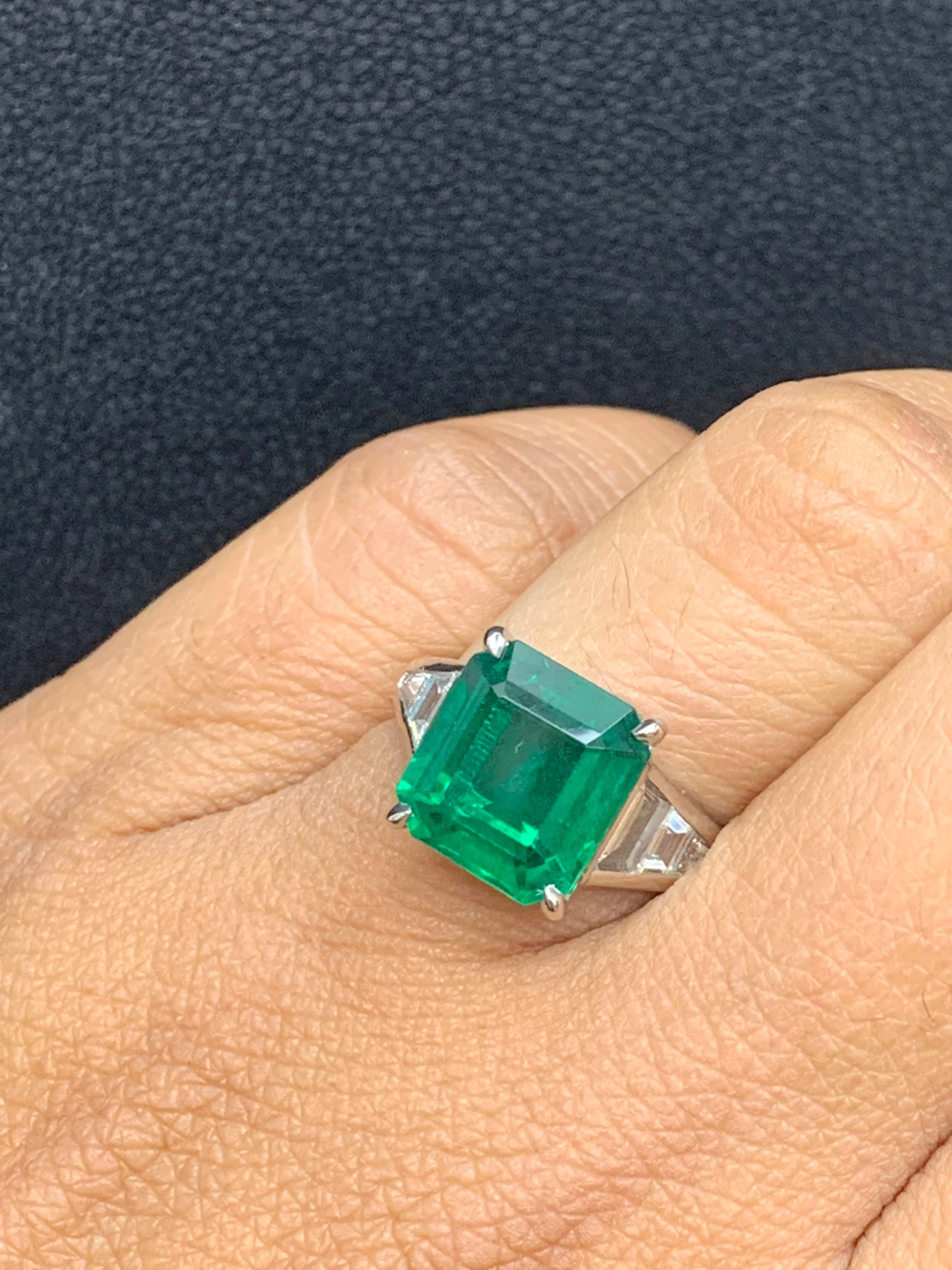 A stunning well-crafted engagement ring showcasing a 4.03-carat  emerald-cut Emerald. Flanking the center diamond are perfectly matched graduating step-cut diamonds, channel set in a polished platinum mounting. 6 Accent diamonds weigh 0.79 carats