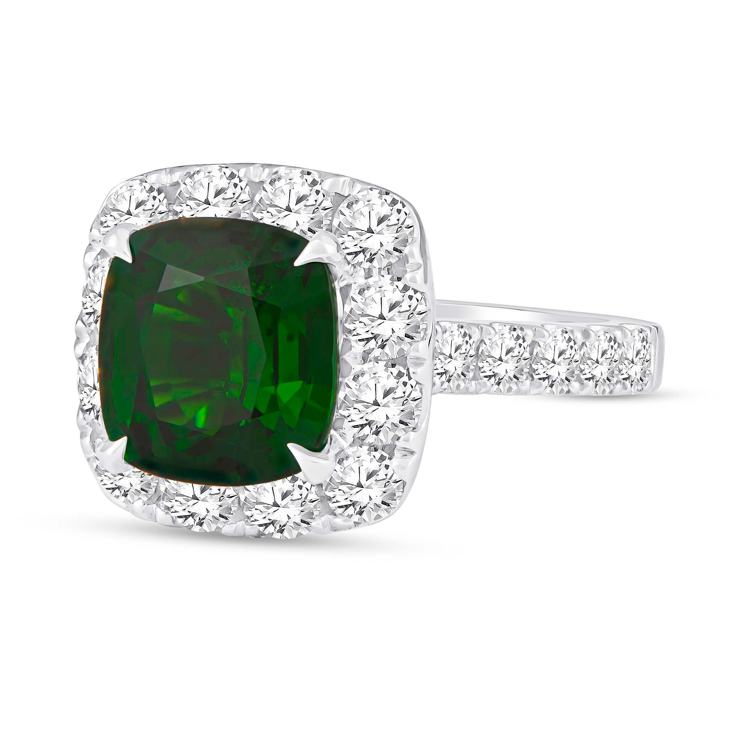 Stunning 18K white gold cathedral style halo ring that features one 4.04 carat mixed cut natural Grossular Tsavorite Garnet. The dark rich green garnet is beautifully surrounded by 1.60 carats of fine round brilliant cut diamonds in halo form. This