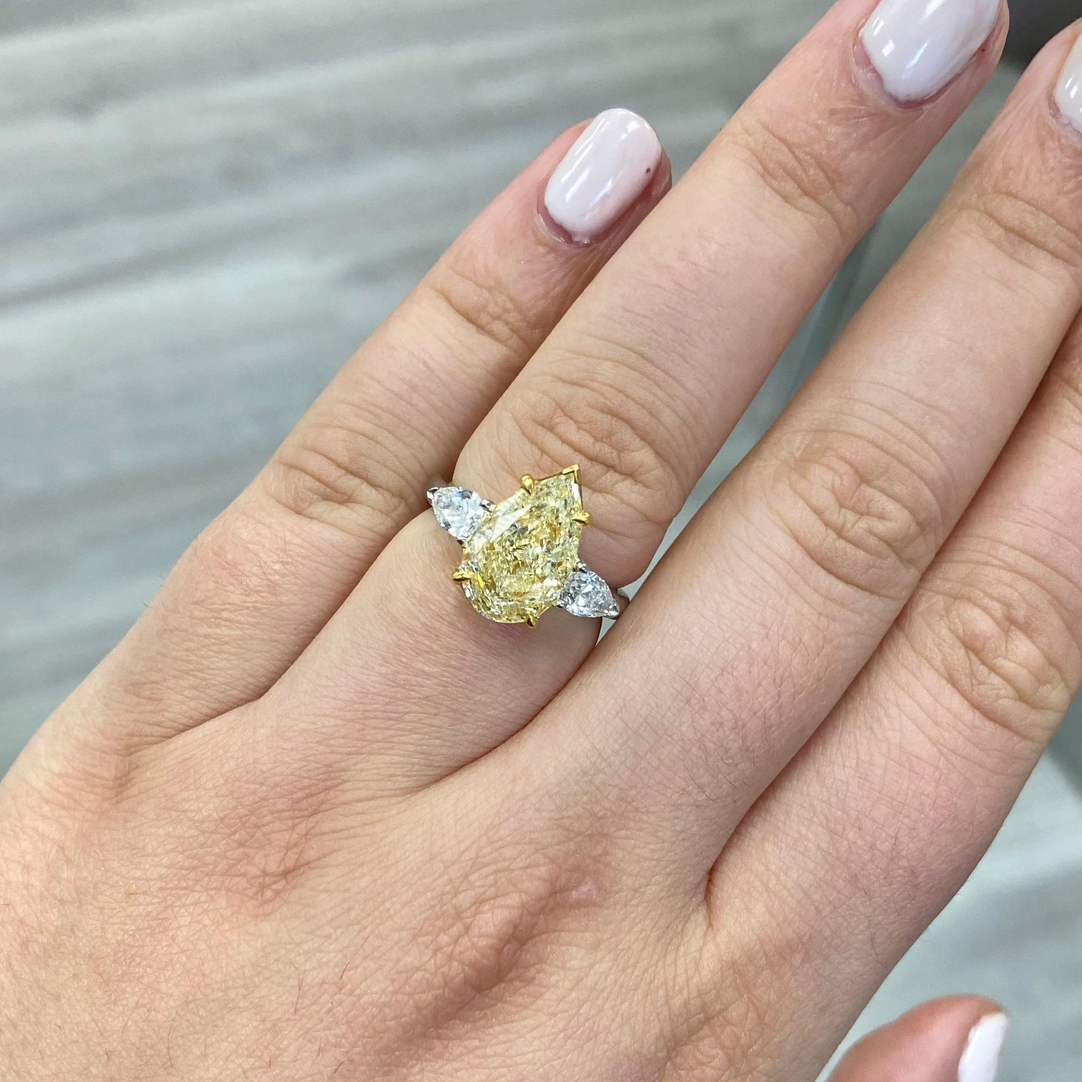 Gorgeous ring with a vibrant 4ct W-X colored pear shape full of life, no bow tie, and a perfect pear shaped model
Set in Platinum and 18kt Yellow Gold with colorless pear shapes going down the sides

Making Extraordinary Attainable with Rare Colors
