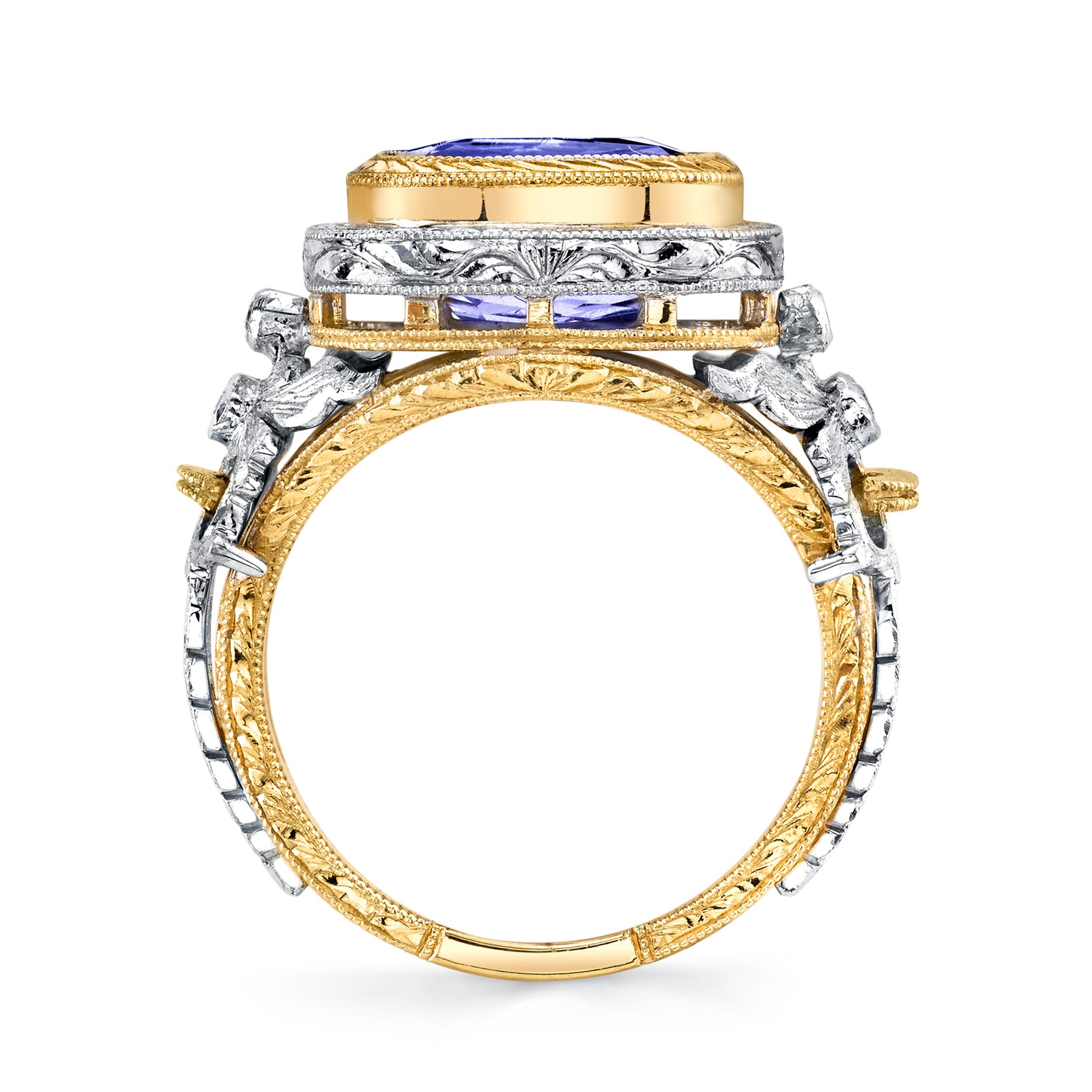 This exquisitely handmade 18k white and yellow gold ring features a gem 4.04 carat tanzanite in a multi-layered, hand engraved 18k yellow gold bezel. The cushion-shaped tanzanite center stone has gorgeous color and is set 