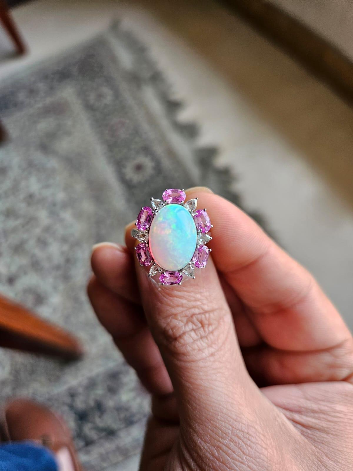 A very gorgeous and beautiful, modern style Opal & Pink Sapphires Engagement Ring set in 18K White Gold & Diamonds. The weight of the Opal is 4.04 carats. The Opal is of Ethiopian origin. The weight of the Pink Sapphires is 1.74 carats. The Pink