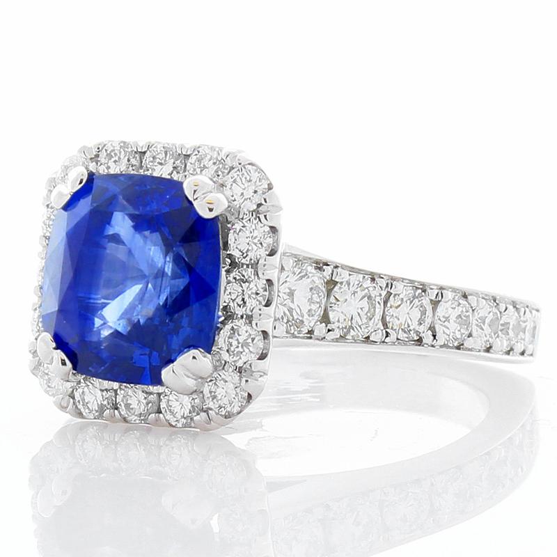 This is a 4.05 carat vibrant royal blue sapphire takes center stage on this luxurious raised basket ring with measurements of 8.6 x 8.2mm. Its gem origin is Sri Lanka. It is polished and faceted to a cushion cut. Its color, transparency, and luster