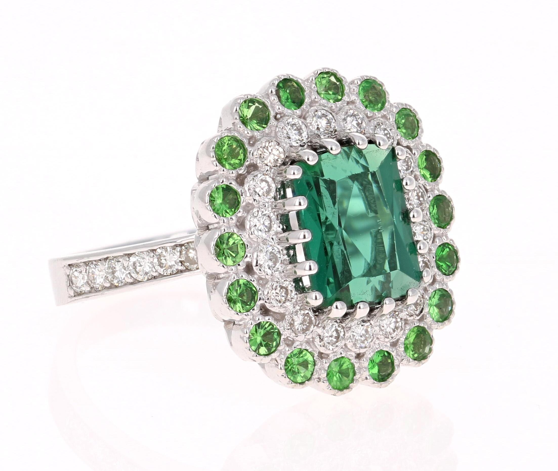 Gorgeous is an under-statement for this beauty! 

This ring has a Emerald Cut Green Tourmaline that weighs 2.81 Carats. Floating around the tourmaline are 30 Round Cut Diamonds weighing 0.65 Carats. (VS/H) 
Alongside the Diamonds are bright and