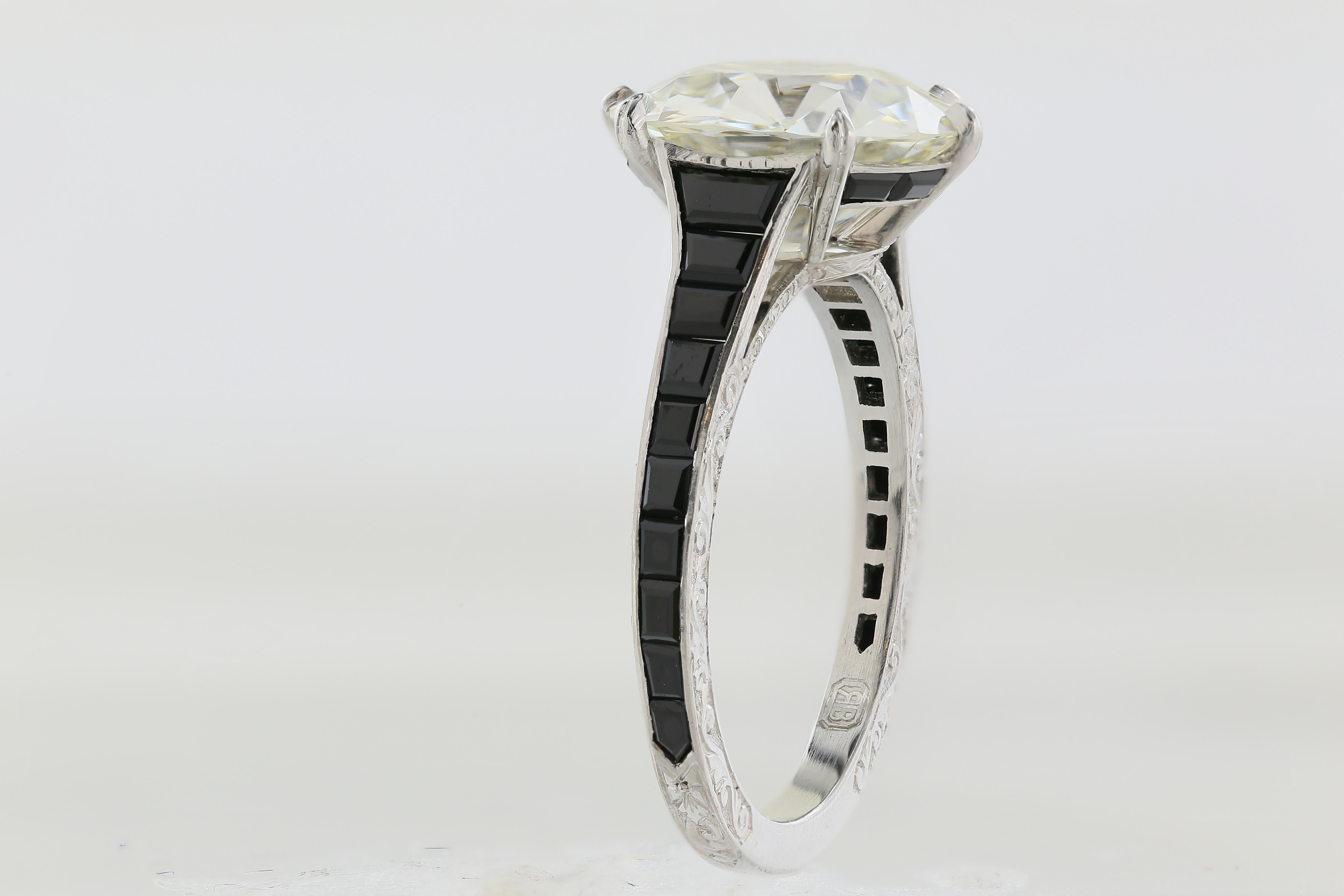 Platinum custom ring featuring 1 Old European cut diamond weighing 4.07 carats with a color and clarity of K VS1 respectively, flanked by 20 step cut black onyx, with filigree detail decorating the under gallery.