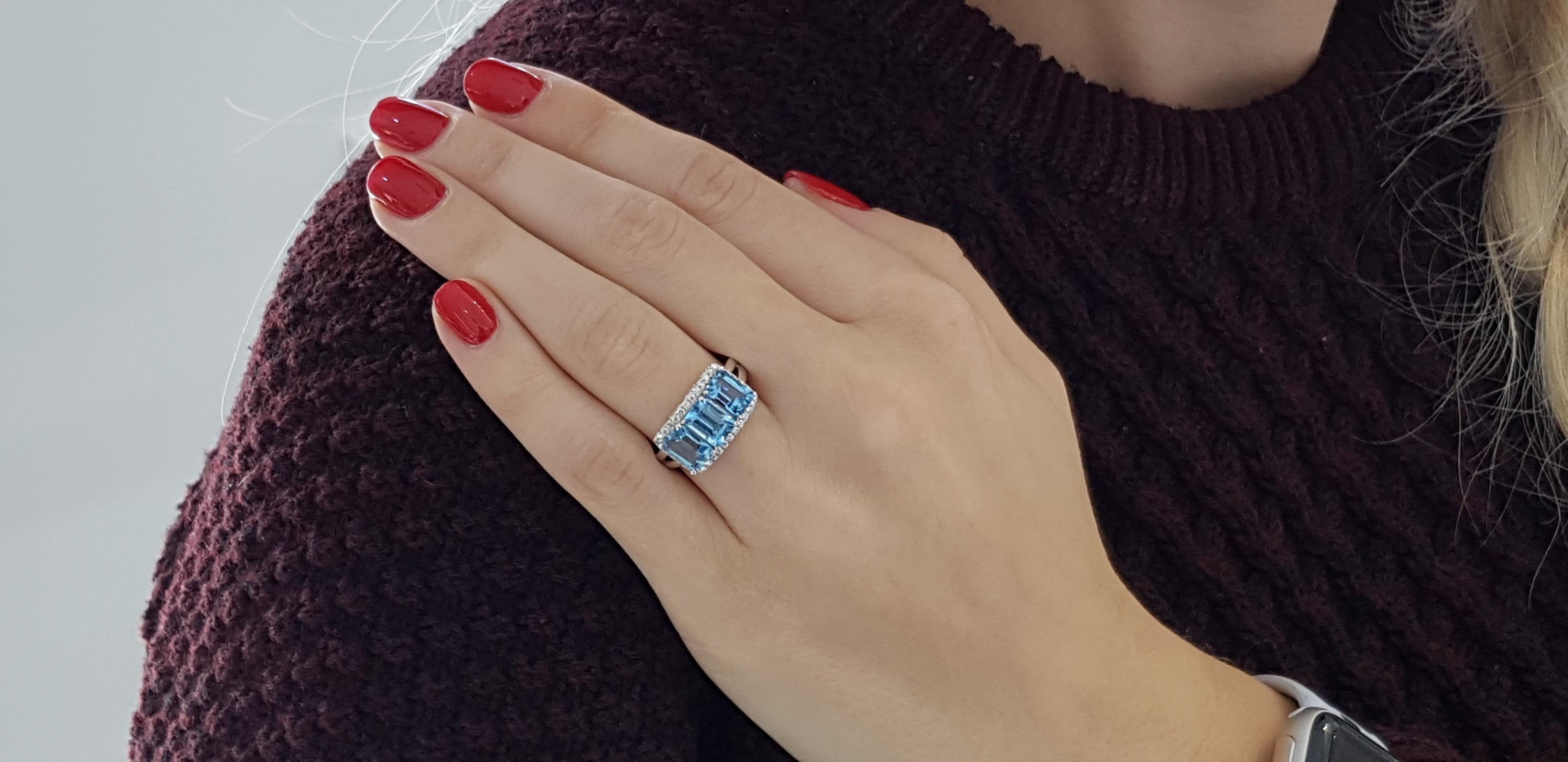 This beautiful 3 stone 3.83 Carat Blue Topaz engagement ring is surrounded by Halo of 0.25 Carat Round White Brilliant Cut Diamonds Color H Clarity SI and set in 18 Karat white gold split shank. Made with a British Hallmark from the London Assay