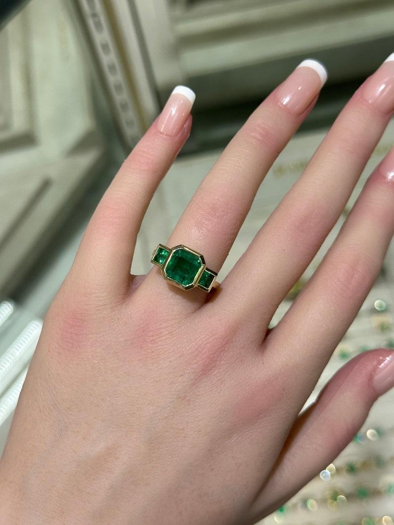 Contemporary 4.08tcw 14K Gold Asscher Cut Emerald Trilogy Ring, Princess Cut Accent, Bezel Se For Sale