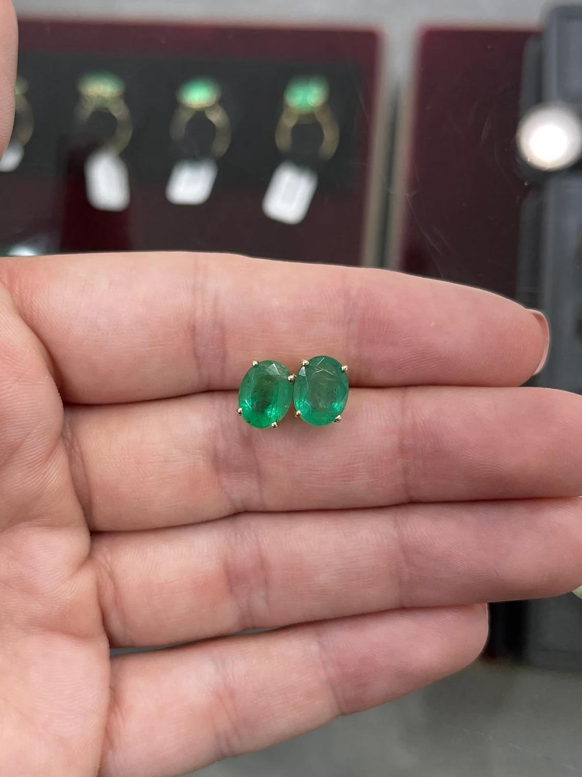 The perfect pair of natural emerald stud earrings. A full 4.08-carats combined, of beautiful Zambian emeralds, cut in the shape of an oval. The pair displays a beautiful medium green color, with good transparency and luster. Crafted in a 14K yellow