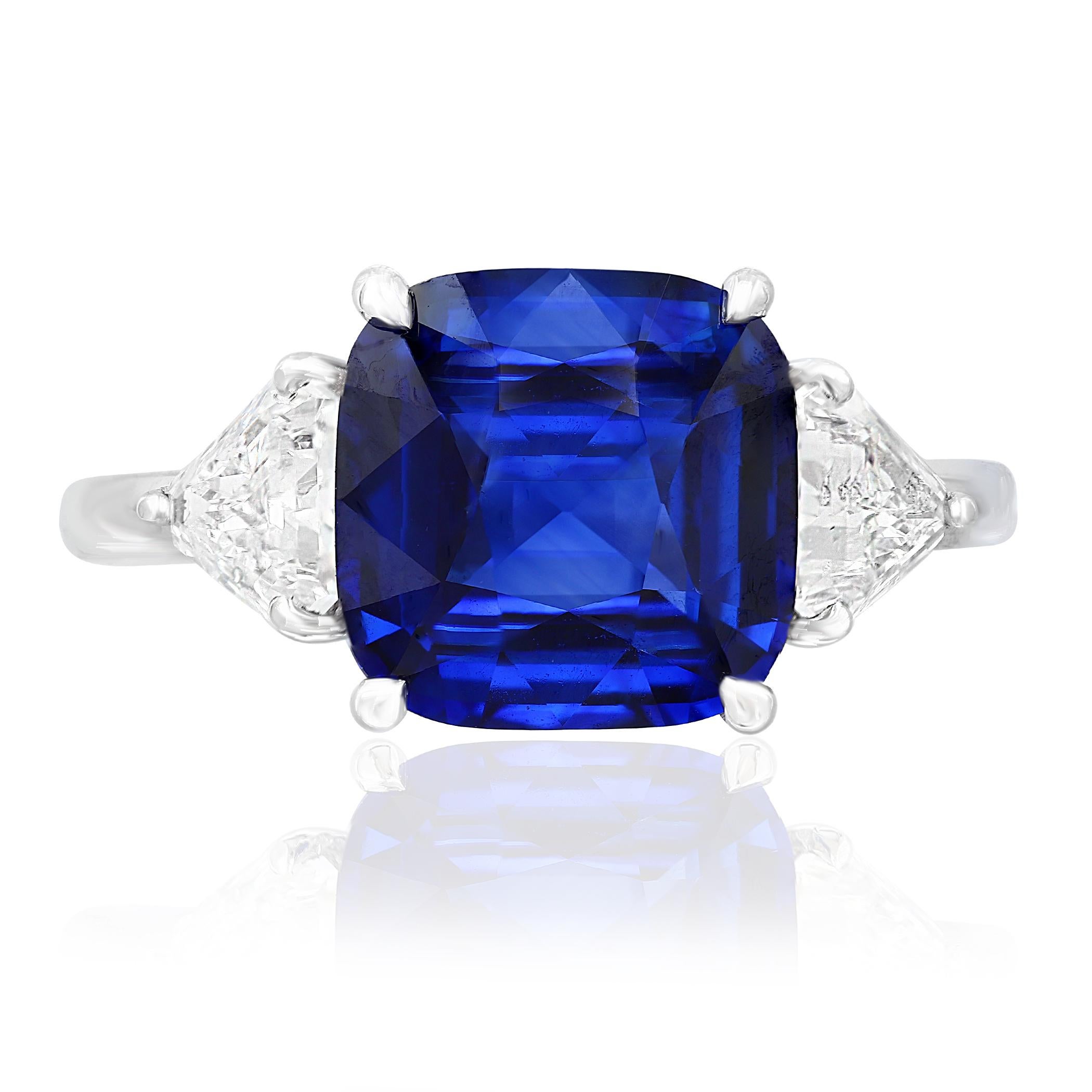 Showcases a Cushion cut, Vibrant color Blue Sapphire weighing 4.09 carats, flanked by two pointed trillion cut diamonds weighing 0.96 carats total. Elegantly set in a polished platinum composition.