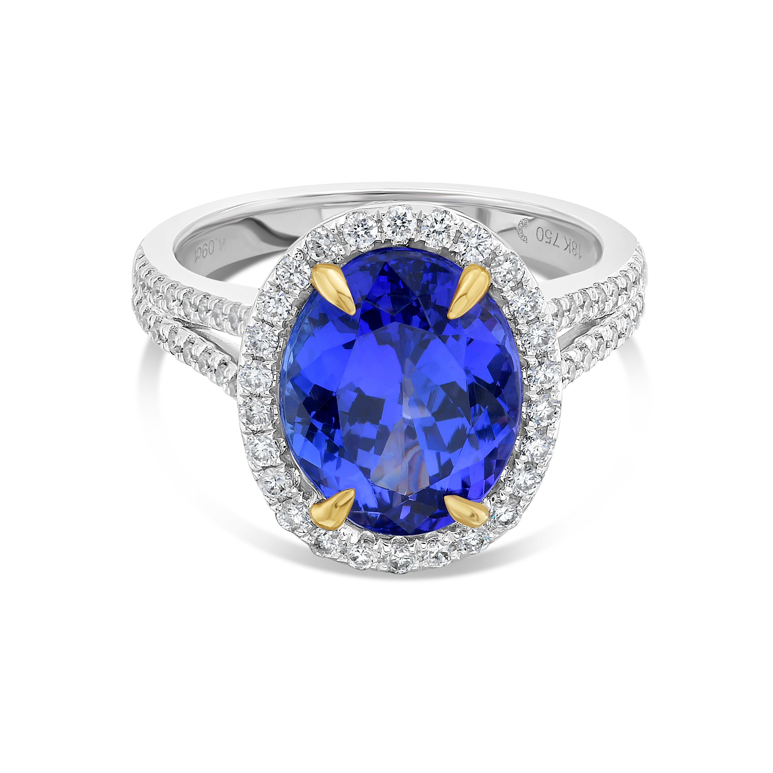 Dieser wunderschöne Cocktailring zeigt einen atemberaubenden ovalen Tansanit von 4.09 Karat mit einem Diamant-Halo, der auf einem geteilten Diamant-Schaft sitzt. 

Dieser Ring ist in 18k Weißgold gefasst, mit 18k Gelbgold Zacken auf dem Mittelstein.