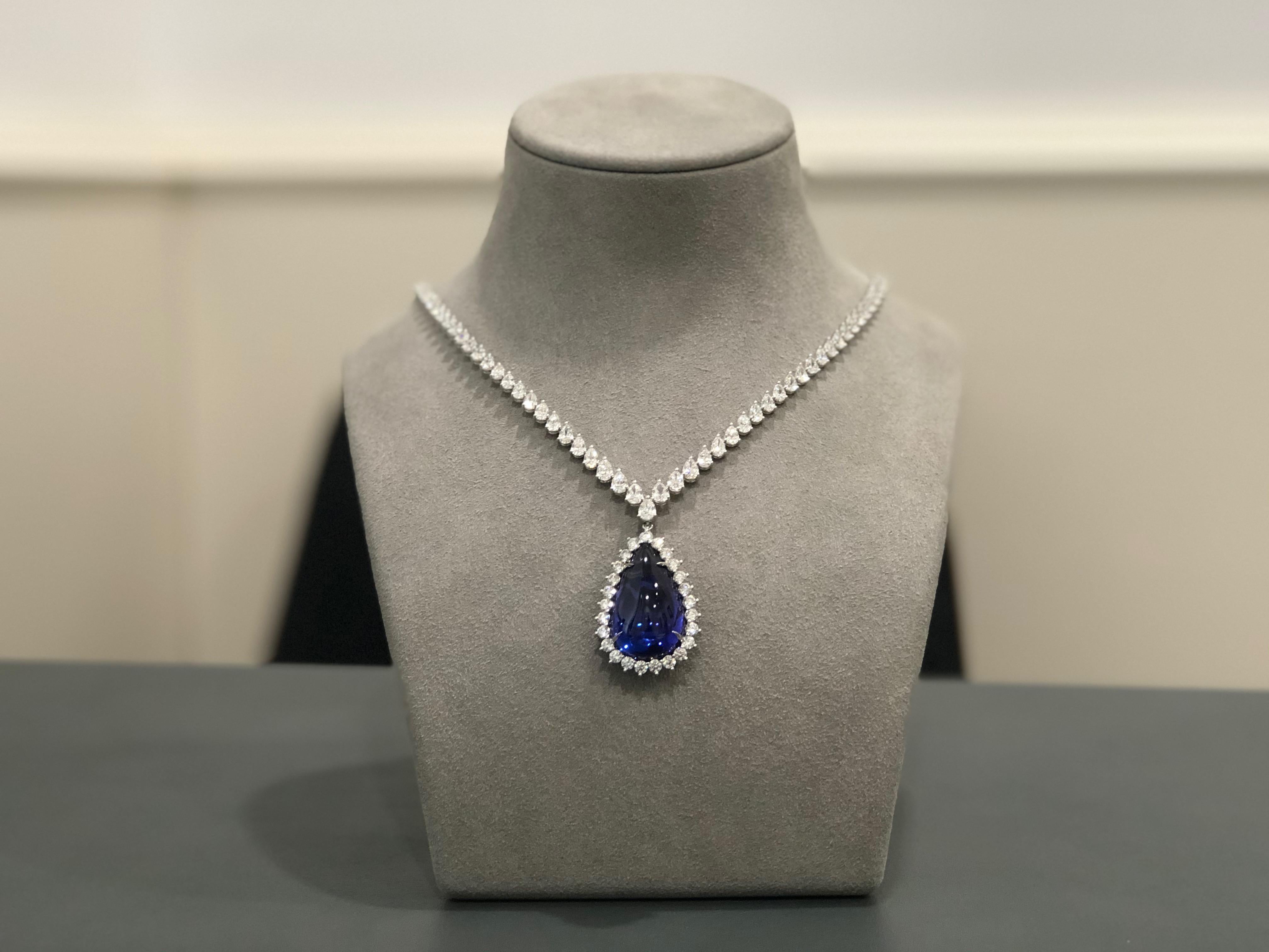 This very important and gorgeous pendant is set with a 40.91 carat pear shape blue cabochon tanzanite. The tanzanite is surrounded by 25 full cut round brilliant diamonds in a 3 prong style setting. The pendant is attached to a stunning diamond