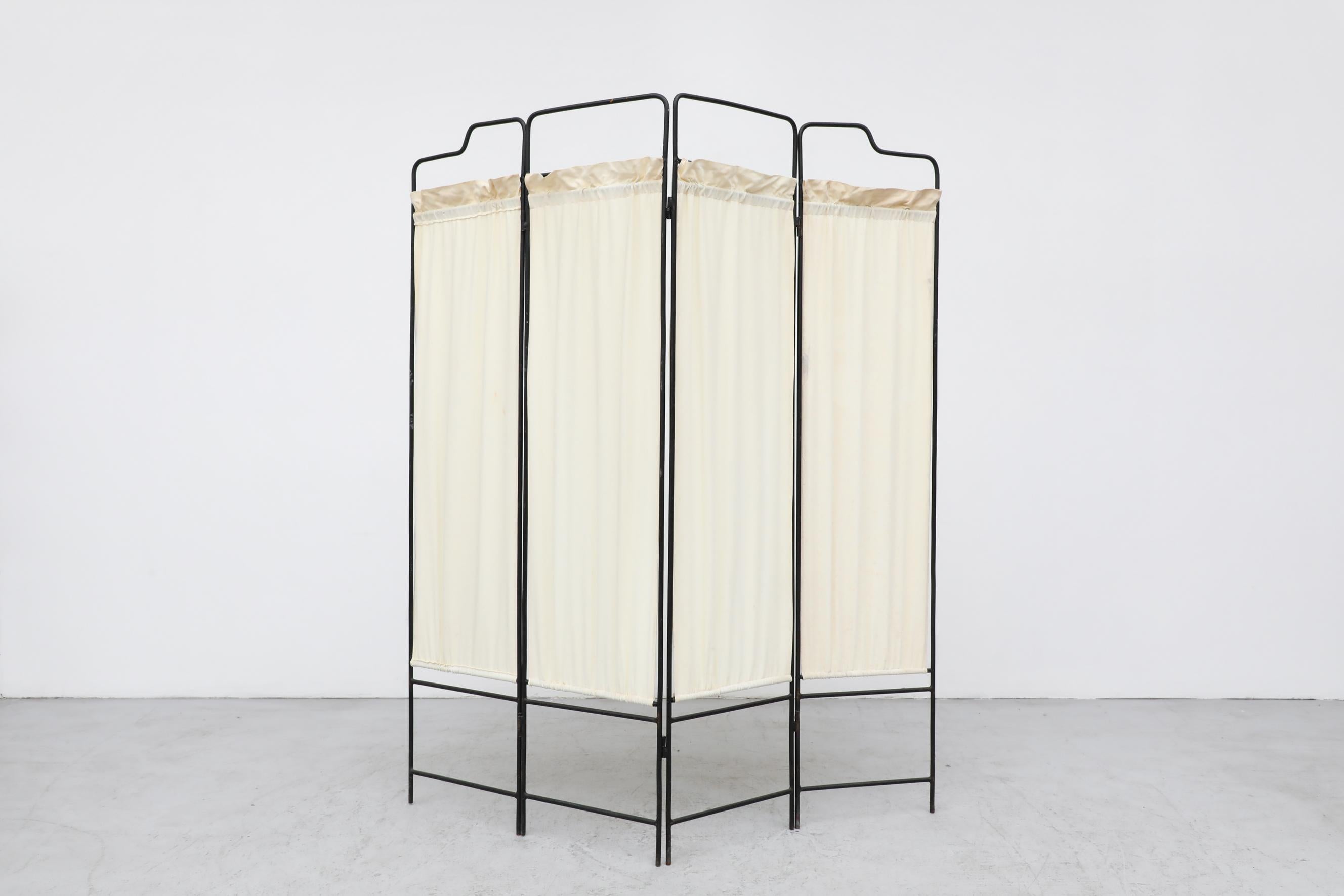 Deco Folding Privacy Screen with Stylized Black Iron Frame. Four Folding Panels each with Inset Cream Fabric, Fabric, not original to the screen, yet visibly vintage. Visible Wear is consistent with its age and use.