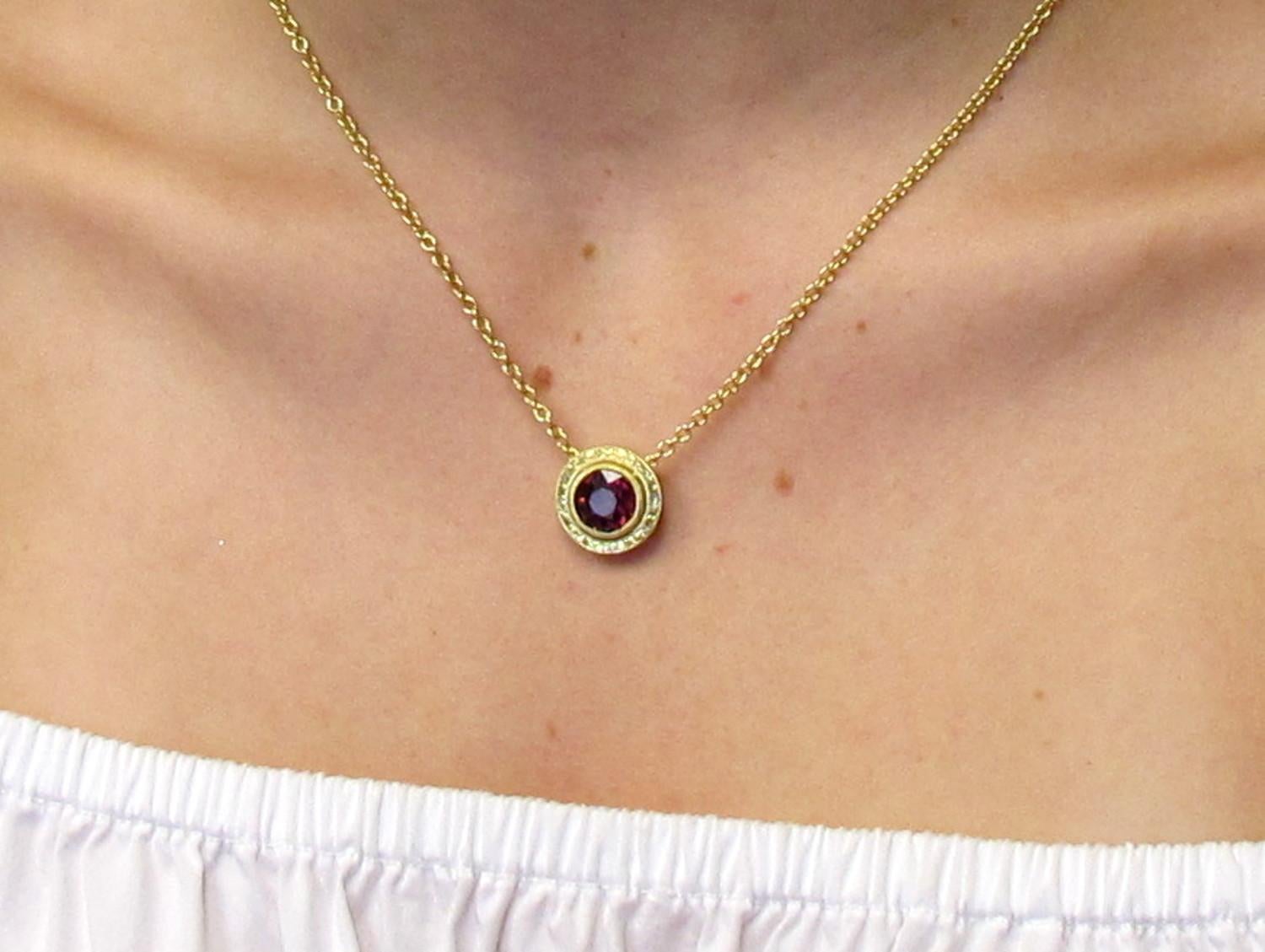This beautifully simple pendant is perfect for everyday wear.  It is set with a vibrant, fuschia color, rhodolite  garnet weighing 4.10 carats. The garnet is set in a frame of hand engraved,  18k yellow gold.  Made by our master jewelers in Los