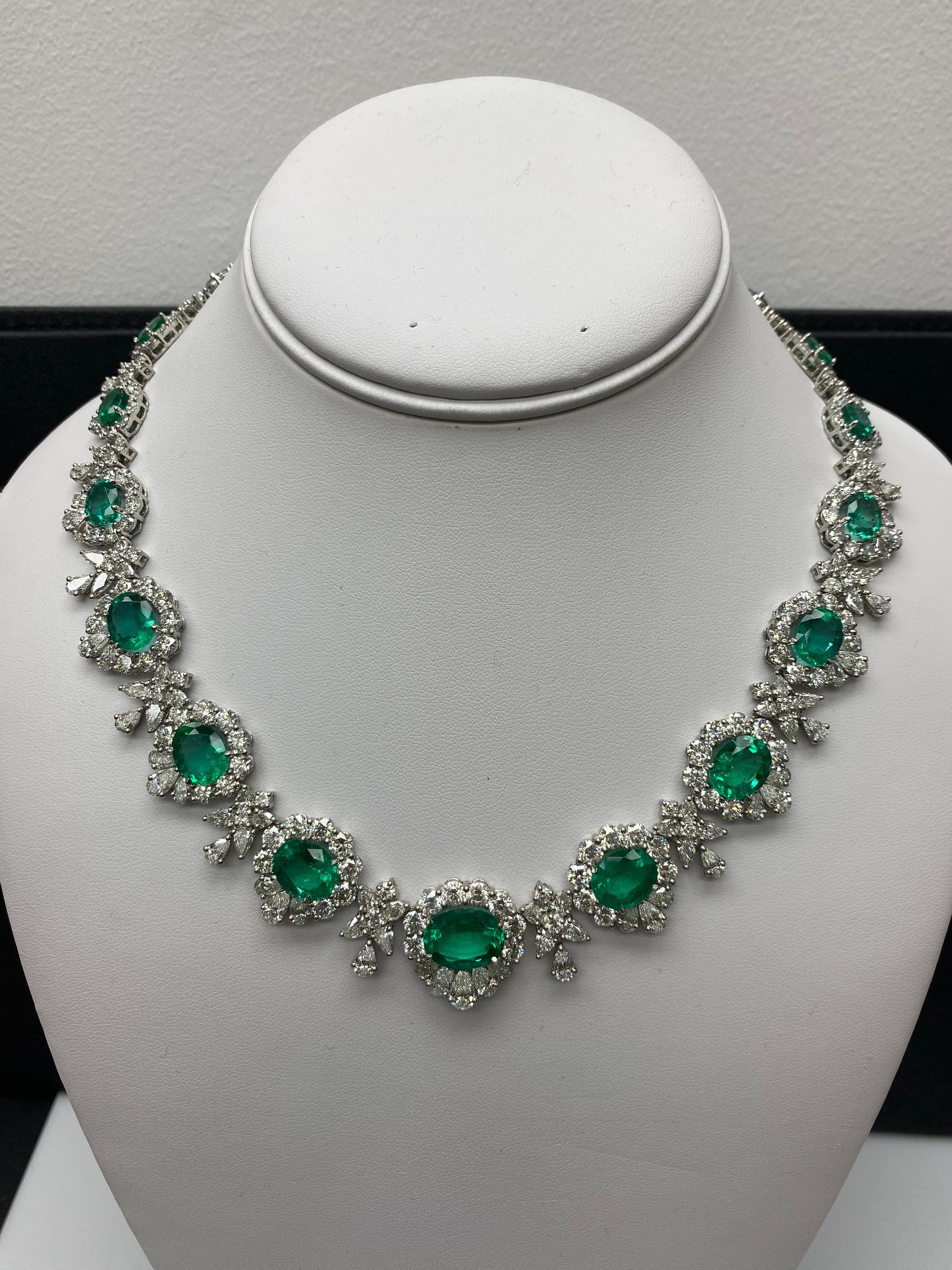Este impresionante collar presenta un cautivador diseño que exhibe vibrantes esmeraldas de talla oval, conocidas por su intenso tono verde. La pieza está intrincadamente elaborada y acentuada por una combinación de brillantes diamantes de talla