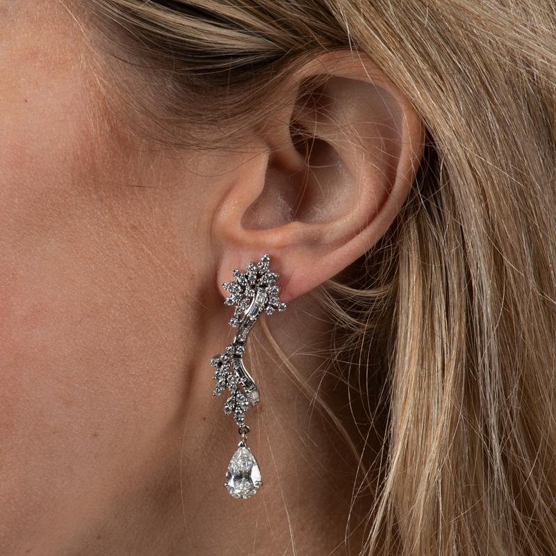 These very unique earrings feature 4.11 carat total weight in two pear shaped natural diamonds accented by 2.00 carat total weight in baguette and round diamonds set in palladium. Friction post with butterfly back. 
Measurements: Approximately 2.25