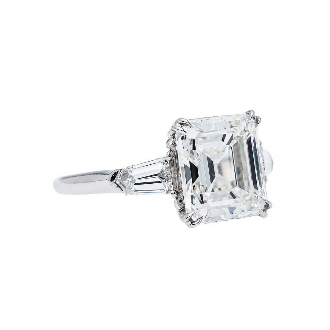 This elegant ring features a 4.12 carat emerald cut diamond that is GIA certified as H color and VVS2 clarity. With perfect proportions the stone illuminates with brilliance creating a sparkle and charm that is undeniable. Flawlessly flanked on