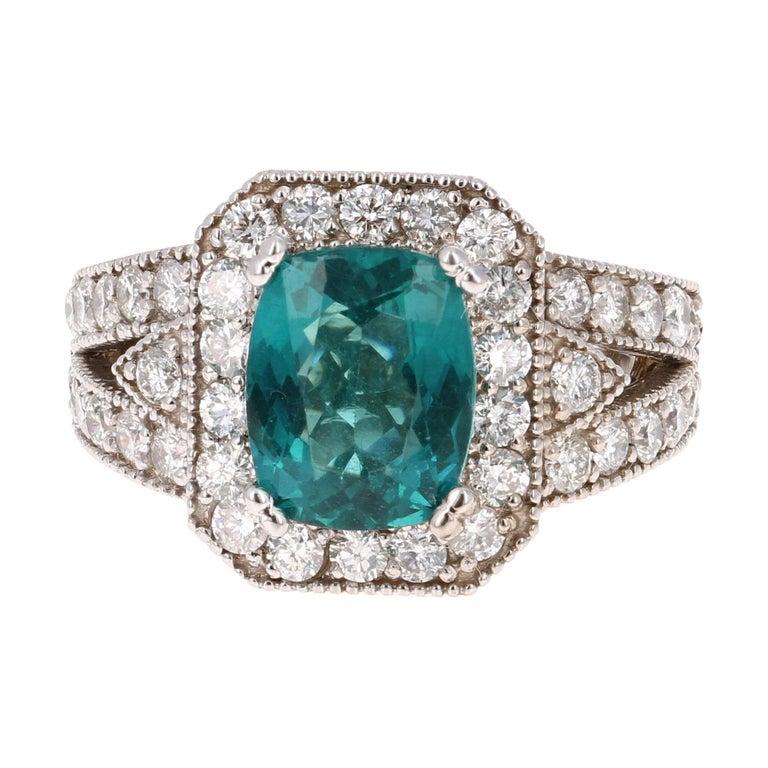 Cette bague est ornée d'une apatite de 2,75 carats à taille coussin au centre de l'anneau, entourée de diamants ronds pesant 1,38 carats (pureté : SI1, couleur : F). Le poids total en carats de la bague est de 4.13 carats.

Il est coulé en or blanc