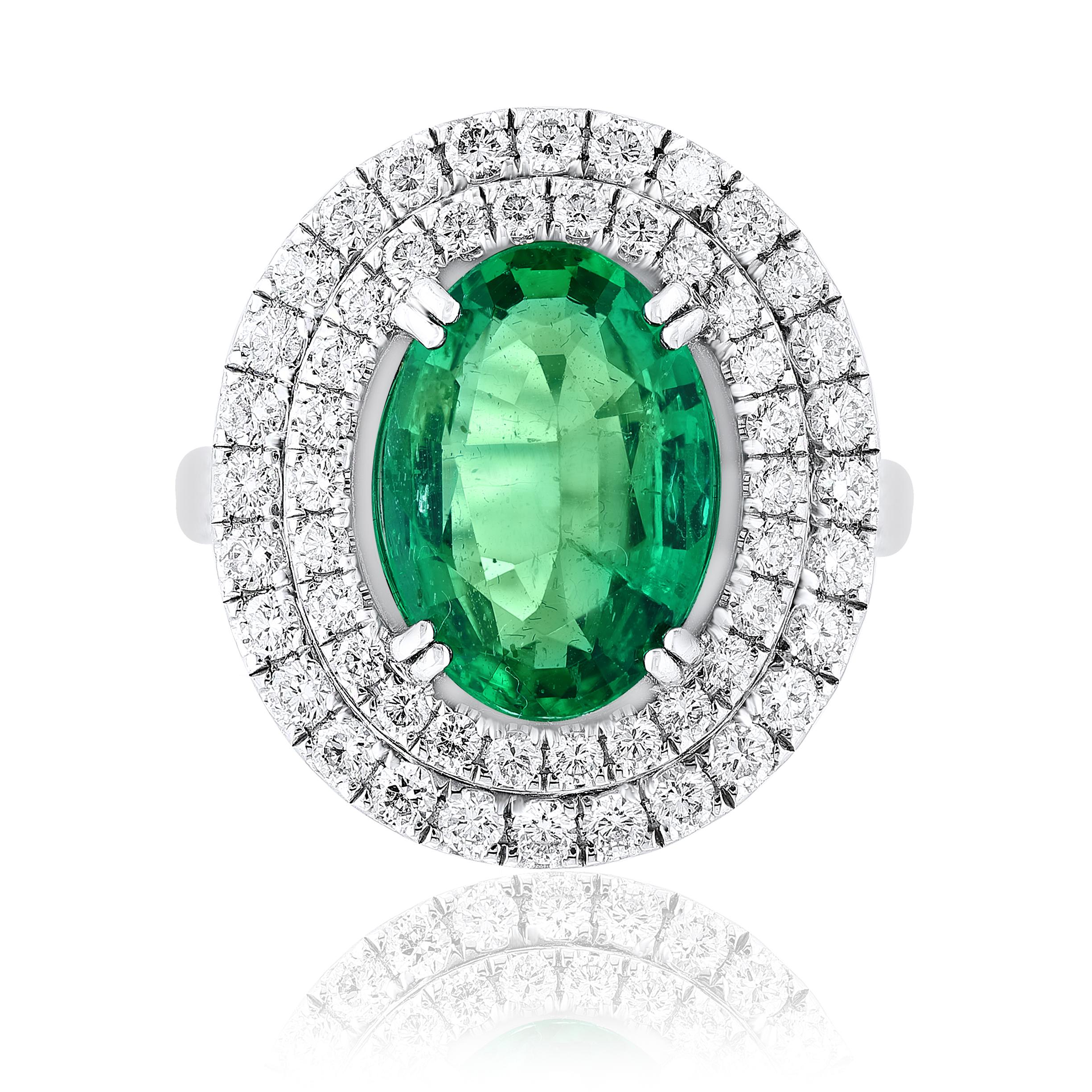 A spectacular engagement ring style showcasing a 4.13-carat oval cut lush green emerald and  Center stone is surrounded by two rows of round brilliant diamonds in an 18k white gold  shank mounting. 94 White diamonds weigh 1.45 carats total. Size 6.5