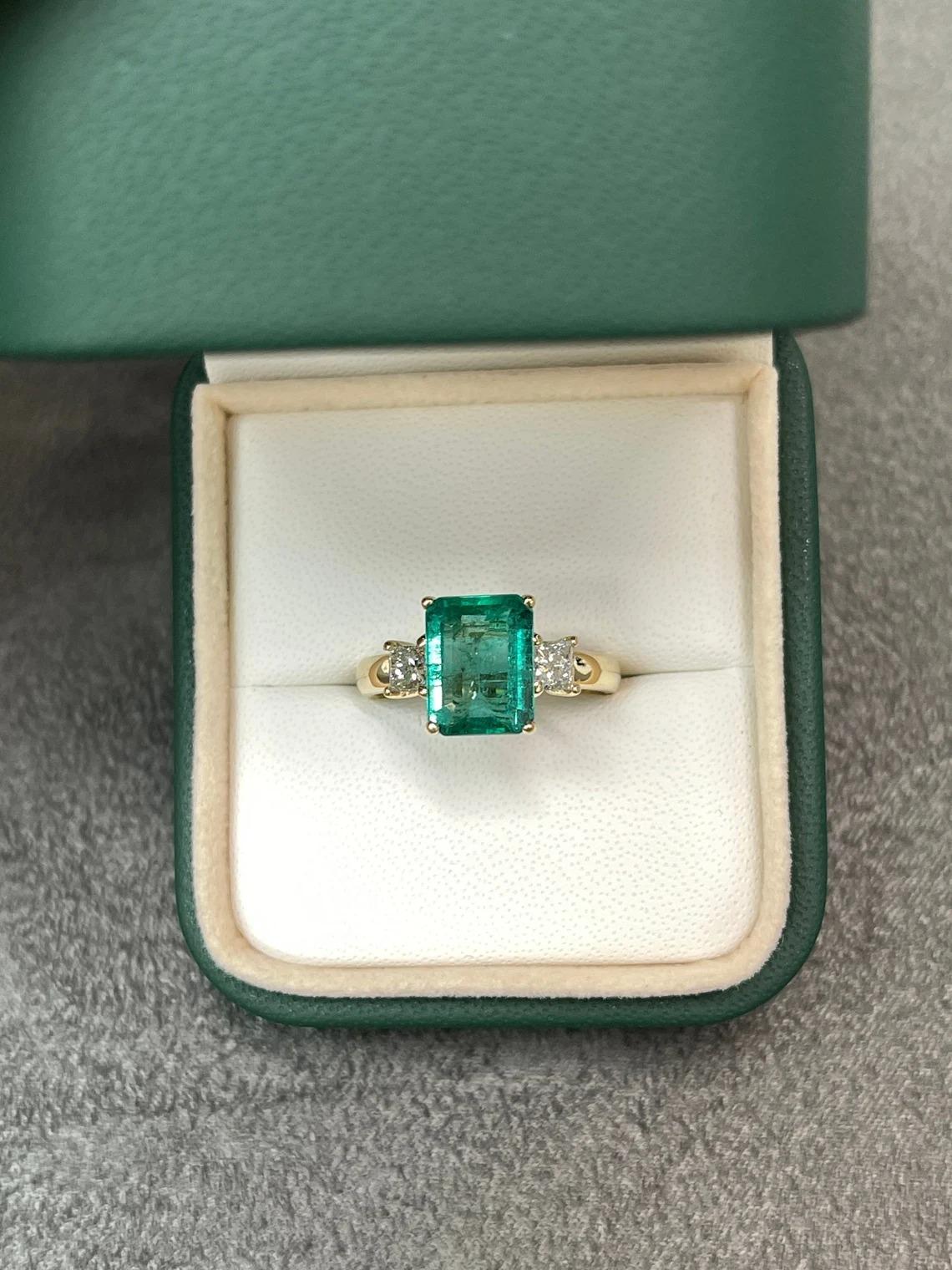 A classic emerald and diamond three stone, engagement, statement, or right-hand ring. Dexterously crafted in gleaming 14K yellow gold this ring features a 3.57-carat natural emerald-emerald cut. Set in a secure prong setting, this extraordinary