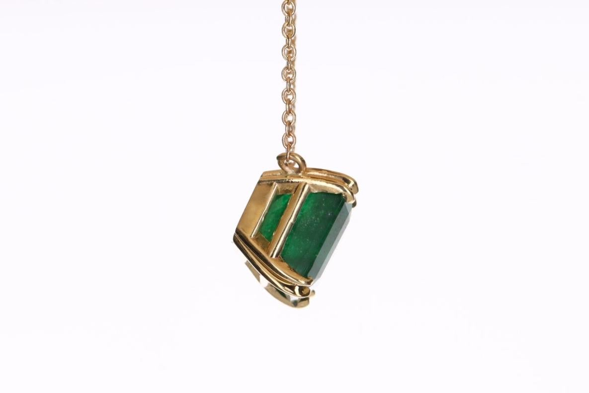 Featured here is a 4.18-carat stunning, Asscher cut emerald necklace in 14K yellow gold. Displayed in the center is a dark green emerald with very good eye clarity, accented by a simple double-prong gold mount, allowing for the emerald to be shown