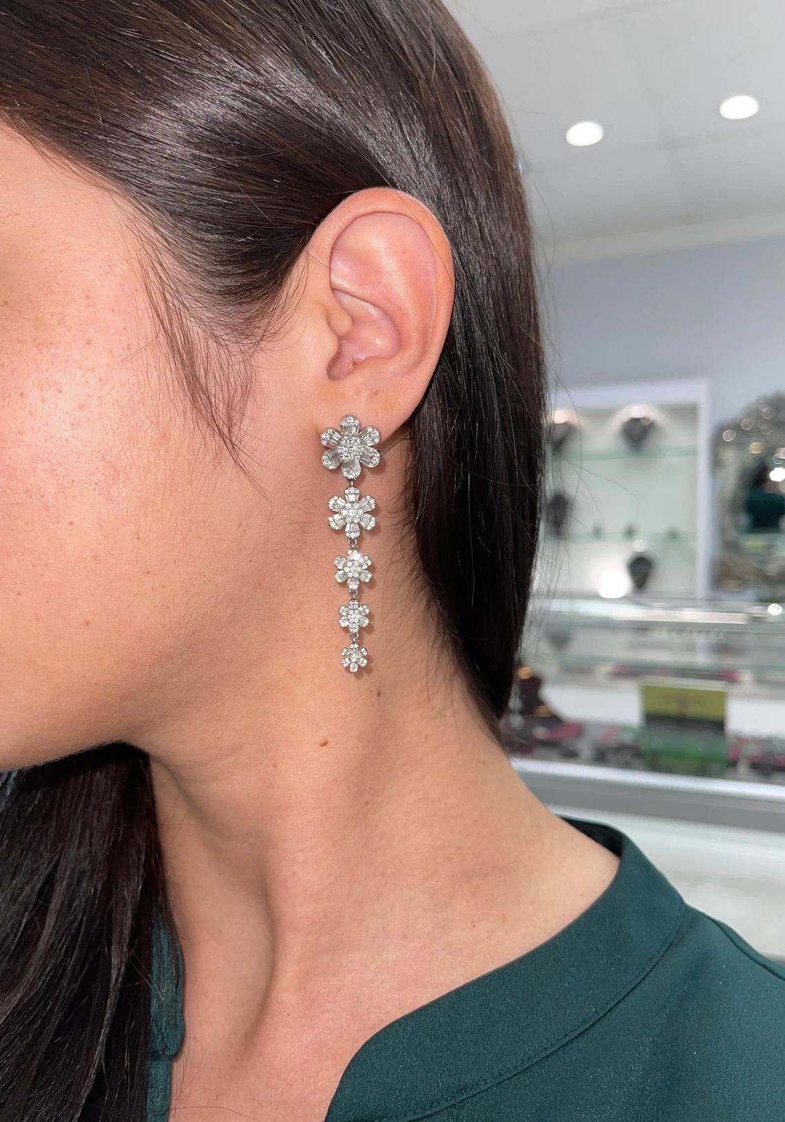 Featured here are 4.18tcw diamond floral chandelier earrings. Five stunning flowers, fully made of diamonds dangle the earlobe in a stunning and chic fashion. Brilliant round diamonds create the stigma, and round and baguette diamonds make the