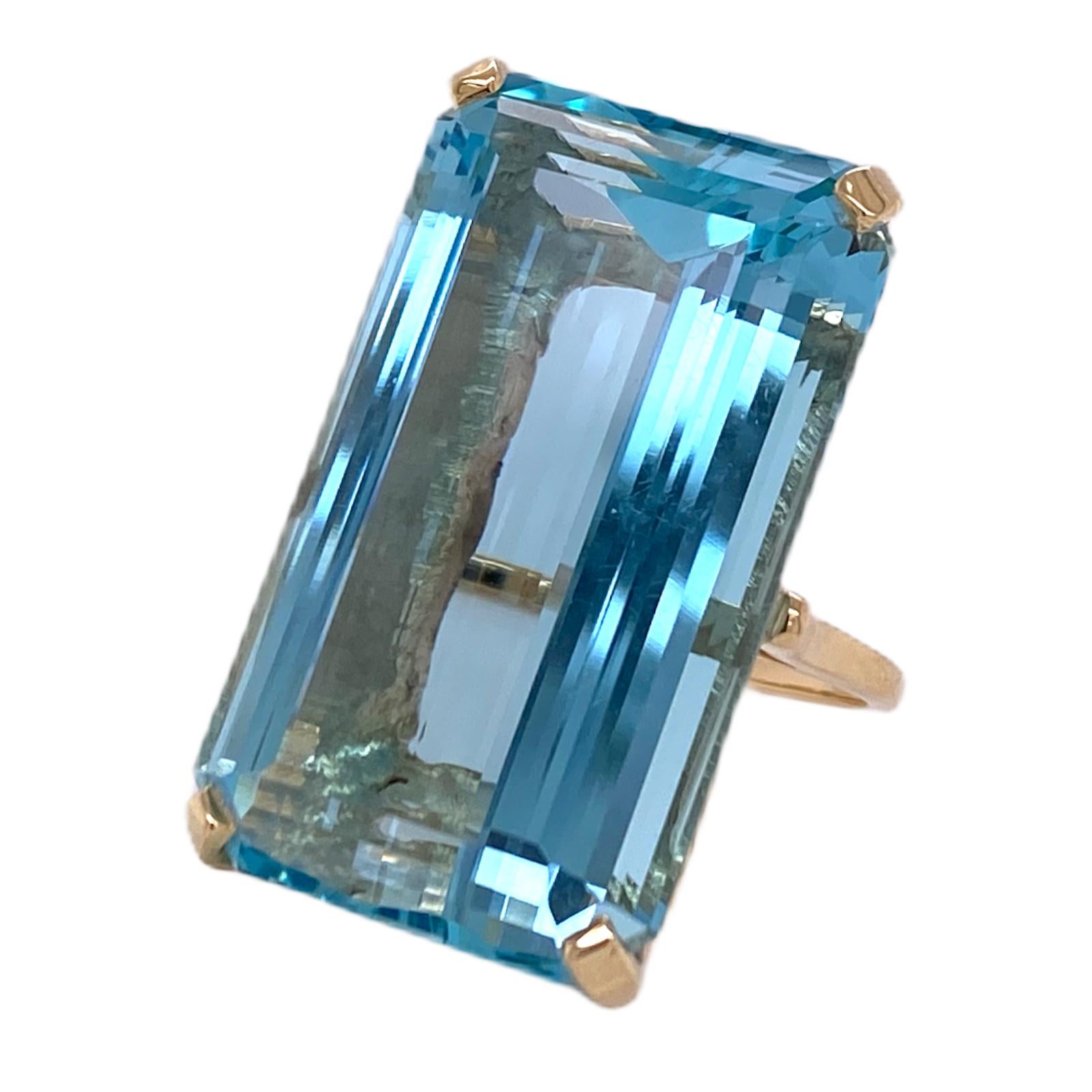 Stunning emerald cut aquamarine gemstone cocktail ring in a handcrafted yellow gold setting. The emerald cut blue aquamarine gemstone weighs 42.03 carats. The stone measures 17 x 28mm and the ring is currently size 6.5 (can be sized). 