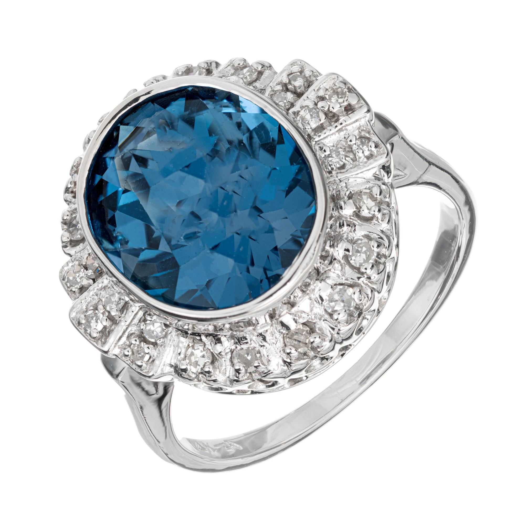 Topaz and Dimond ring. 4.20 Carat oval topaz with a halo of 24 round diamonds in a 14k white gold setting.  

1 oval blue topaz, approx. 4.20cts
24 round diamonds, H-I SI approx. .20cts
Size 6.75 and sizable
14k white gold
Stamped: 14k
6.4
