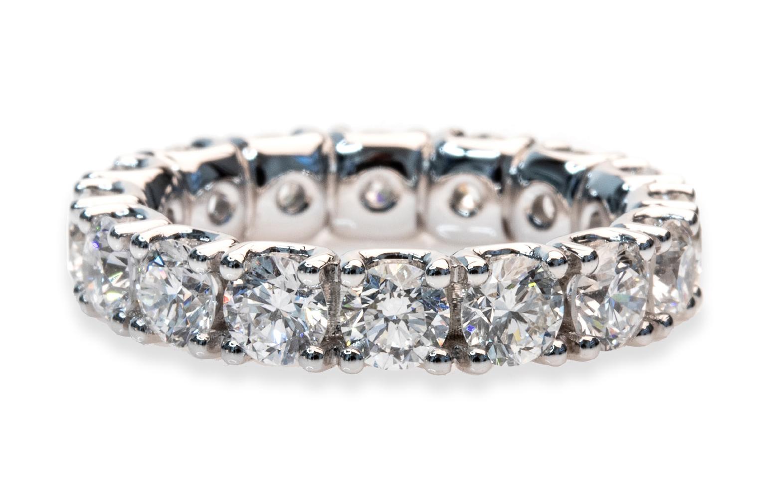 This stunning ring is an Eternity Band, beautifully handcrafted in Italy with a total carat weight of 4.20 carats. The band is made of lustrous 18K white gold, showcasing a series of round diamonds seamlessly set around the entire circumference. The