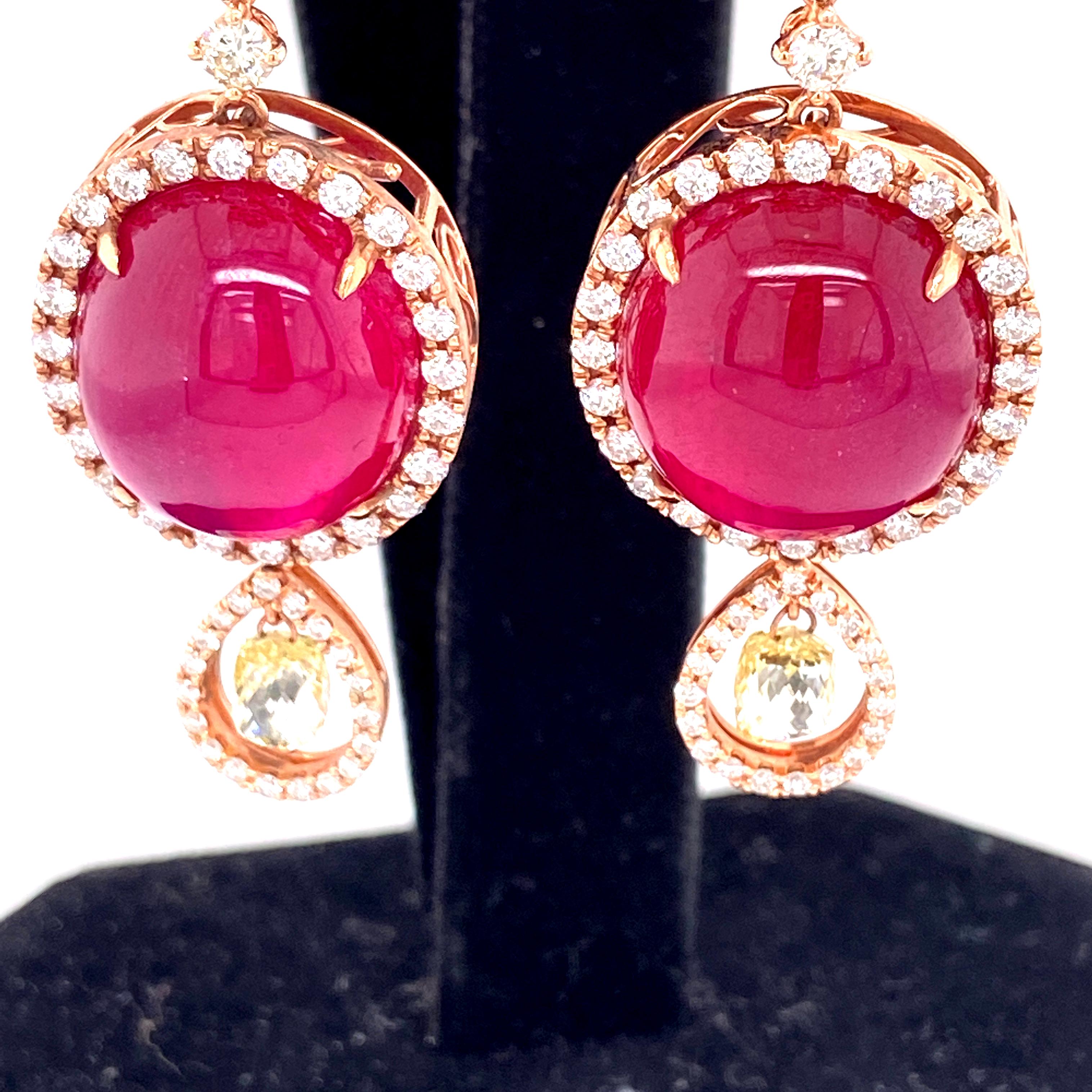 42.02 Carat Ruby Cabochon, Pink Diamond, and Diamond Briolette Gold Earrings:

A unique jewel, it features a beautiful pair of ruby cabochons weighing 42.02 carats surrounded by a halo of white diamonds weighing 1.65 carats, with yellow diamond