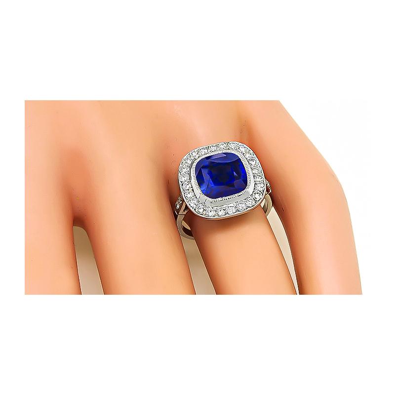 This is a stunning platinum engagement ring. The ring is centered with a lovely cushion cut Ceylon sapphire that weighs approximately 4.20ct. The sapphire is accentuated by sparkling round cut diamonds that weigh approximately 0.70ct. The color of