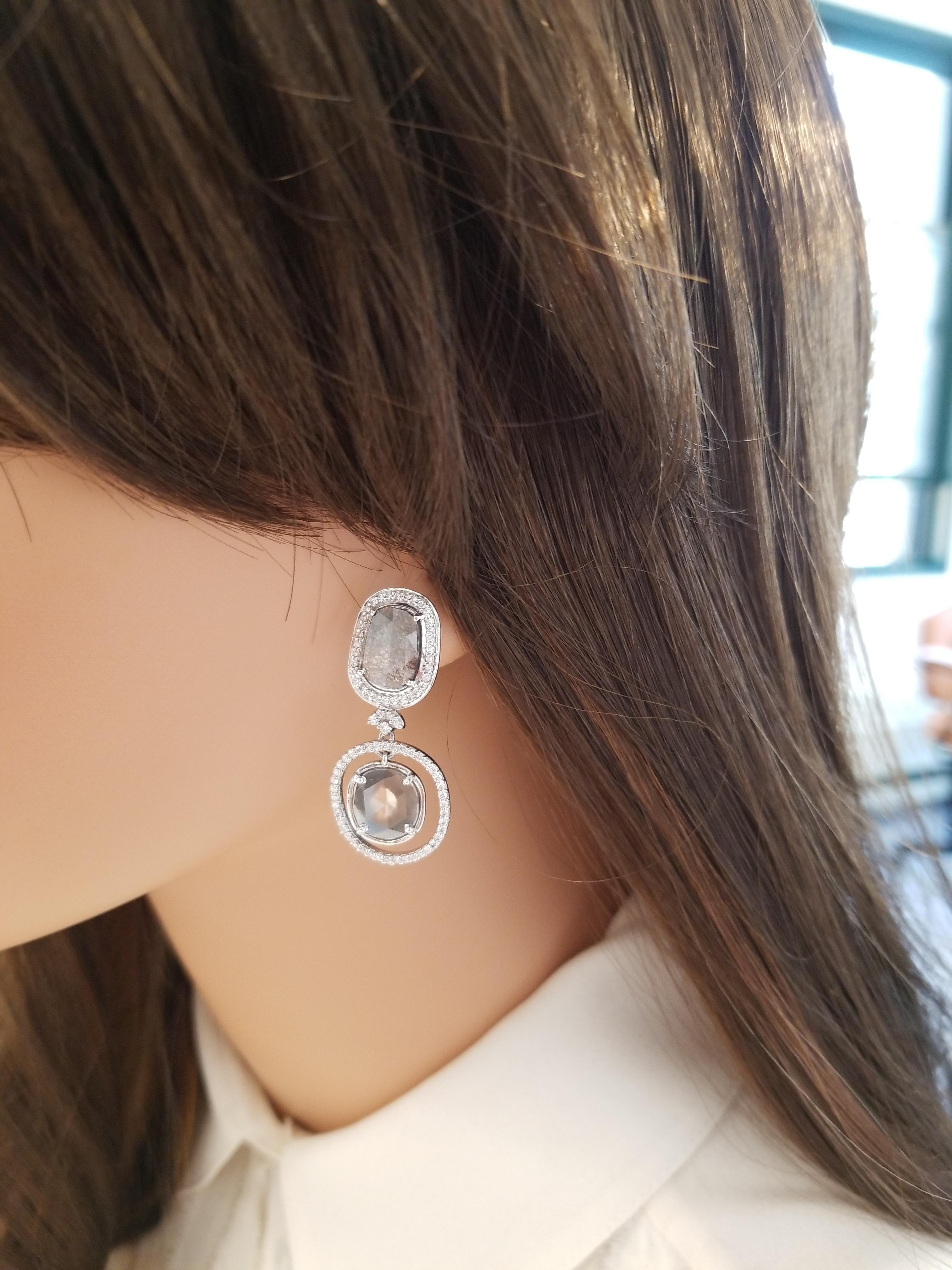 Diese Ohrringe sind mit 4 schimmernden, facettierten schwarzen Diamanten von insgesamt 4,21 Karat besetzt. Diese Diamanten werden von funkelnden weißen Diamanten mit rundem Brillantschliff umrahmt, die in Zacken gefasst sind und einen schillernden