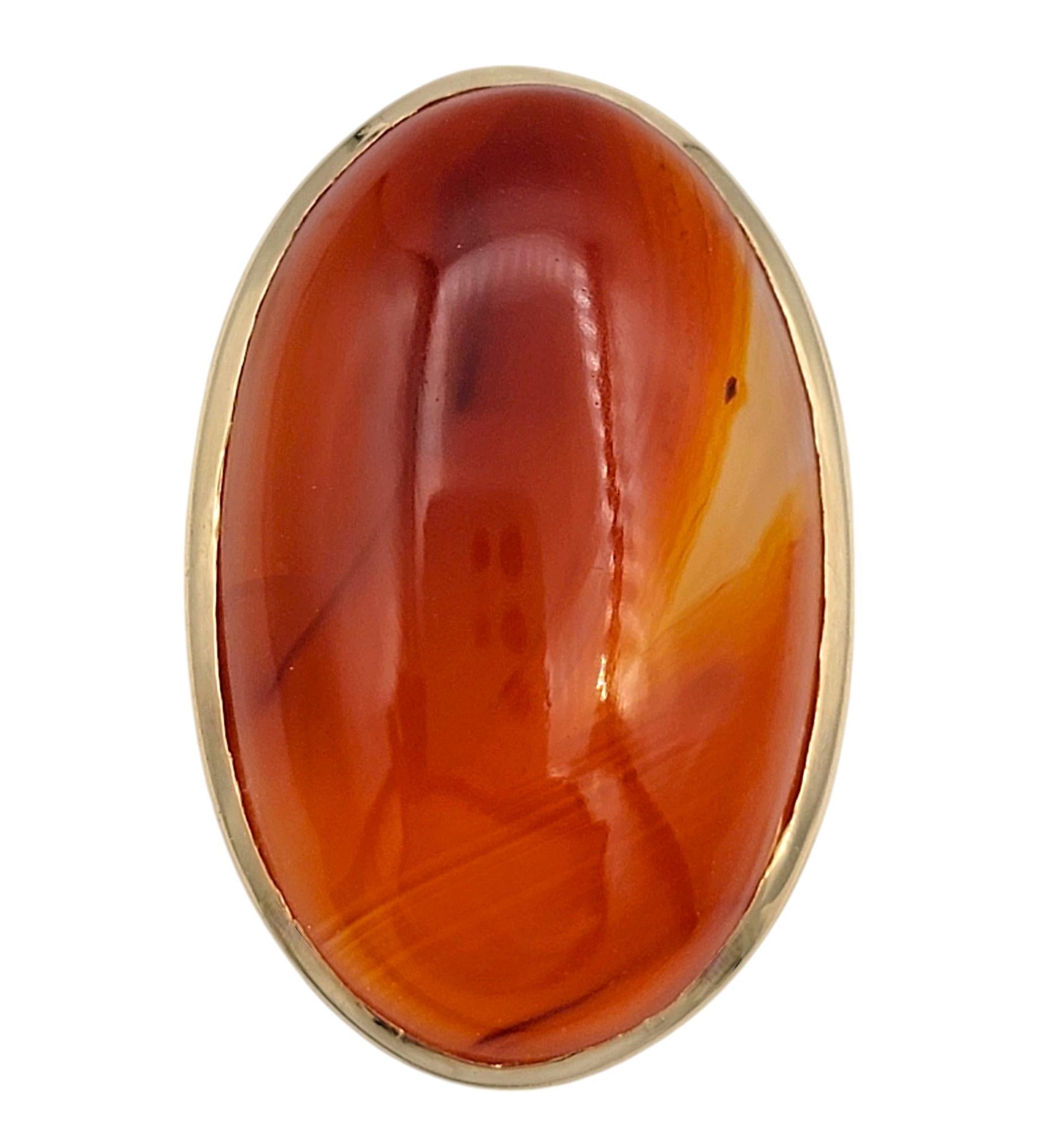 Taille de l'anneau : 14.5

Entrez dans un monde d'élégance audacieuse avec cette extraordinaire bague de déclaration, mettant en vedette un cabochon d'agate ovale hypnotisant. Sertie dans un luxueux or jaune 14 carats, cette pièce étonnante présente