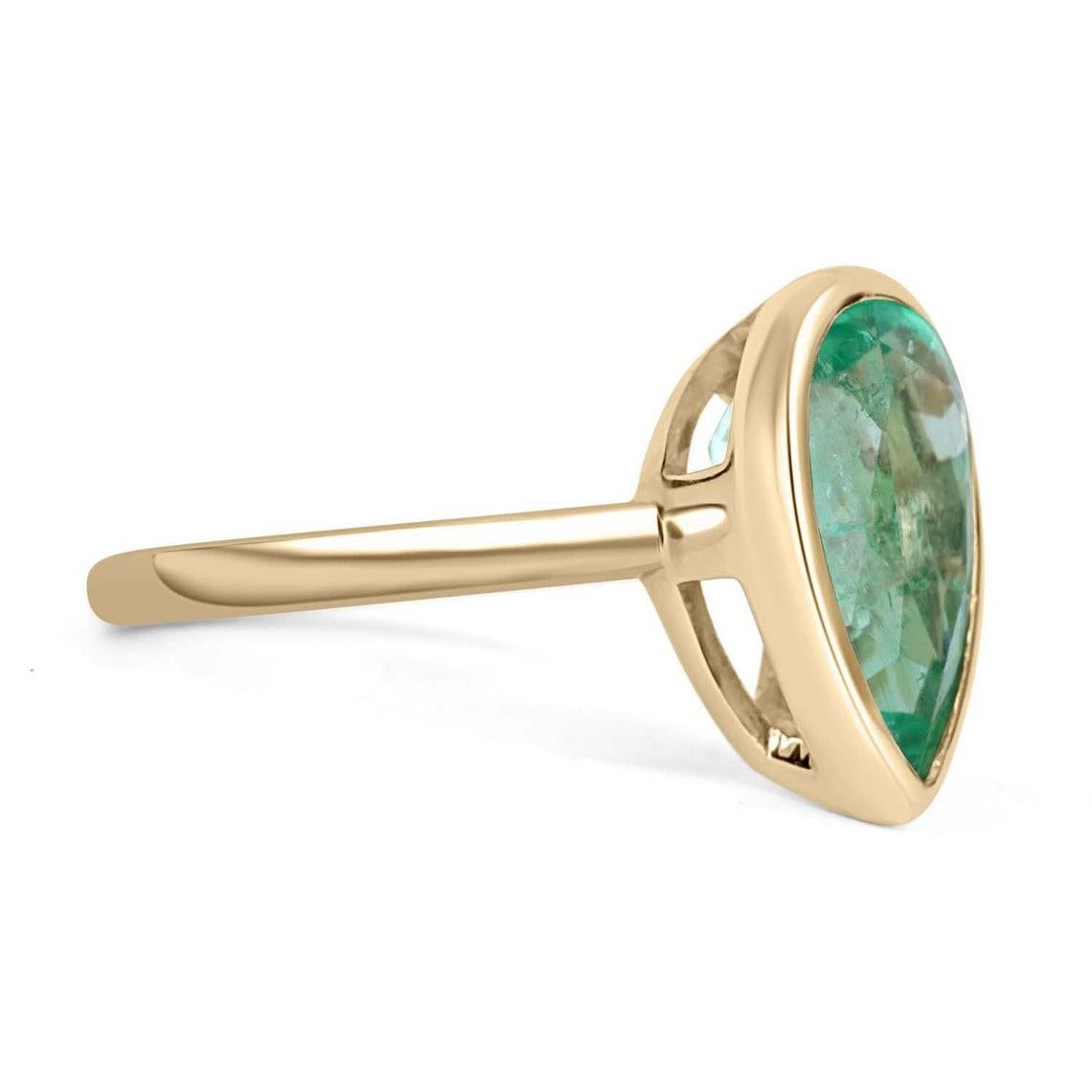 This ring is not for the faint of heart! Displayed is a Colombian emerald bezel-set, teardrop solitaire ring in 14K gold. This gorgeous solitaire ring carries a full 4.22-carat emerald that will have you gazing at its mystic beauty. This large gem