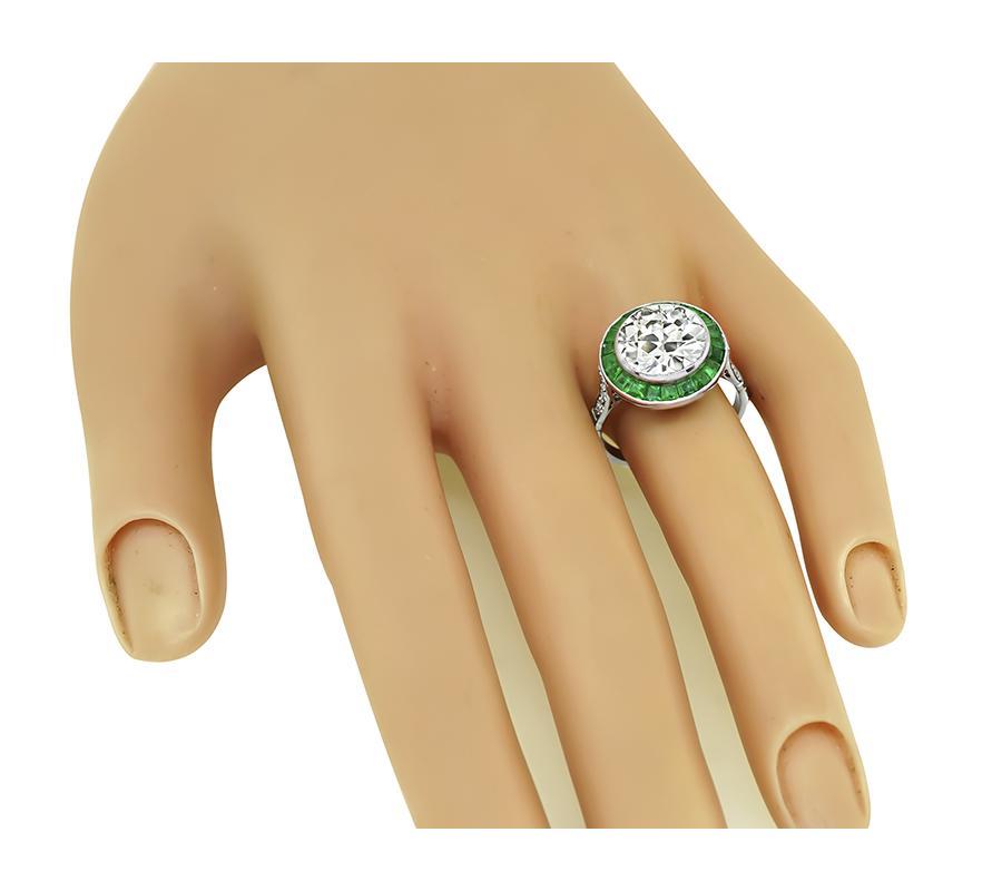 This is an elegant platinum halo engagement ring. The ring is centered with sparkling old mine cut diamond that weighs approximately 4.22ct. The color of the diamond is M with VS clarity. The center diamond is accentuated by lovely emerald and