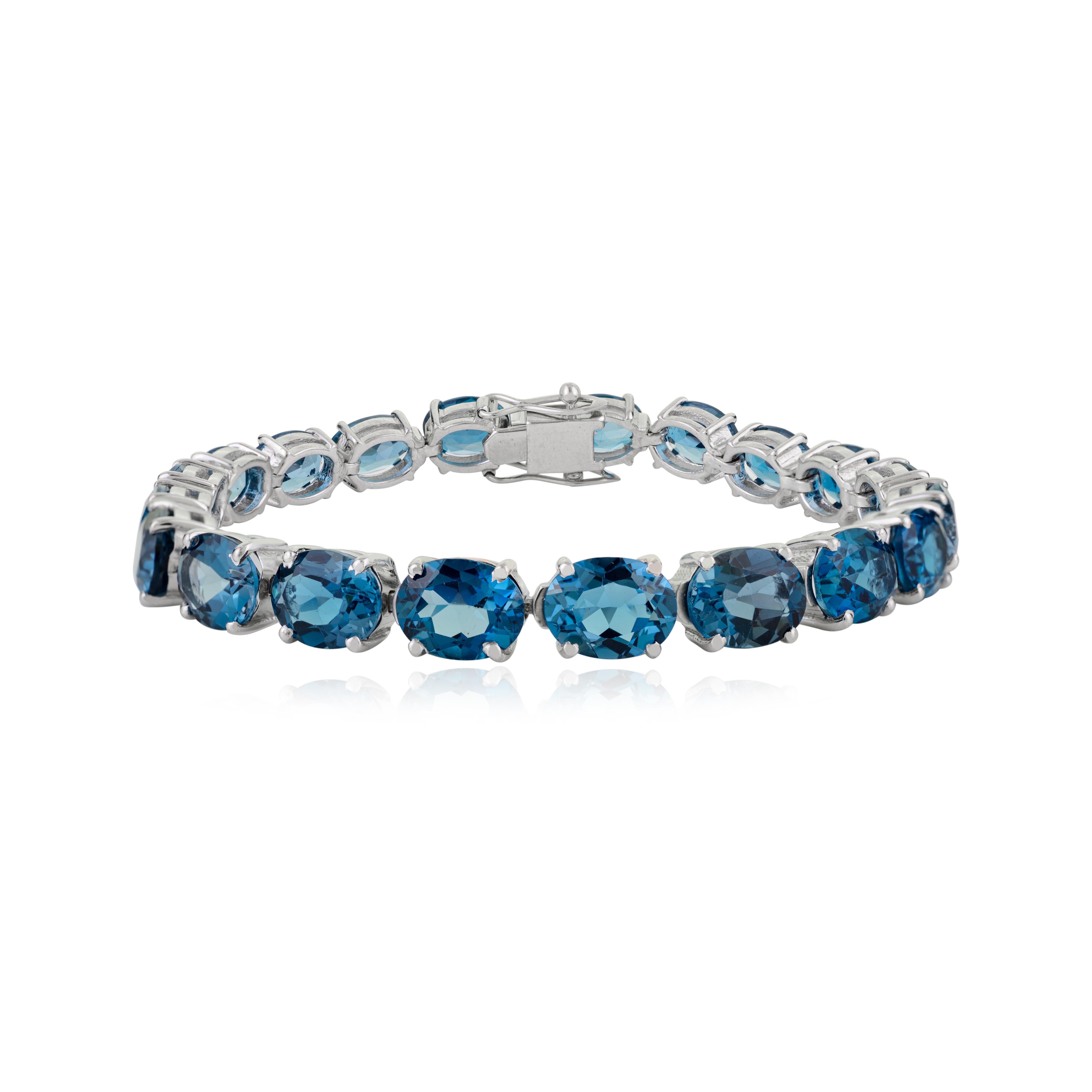 Dieses elegante Tennisarmband mit natürlichem Londoner Blautopas ist aus massivem 925er Sterlingsilber gefertigt. Er besteht aus wunderschönen ovalen Steinen, die jeweils 9x7 mm groß sind und ein Gesamtgewicht von 42,45 Karat haben. Das Design