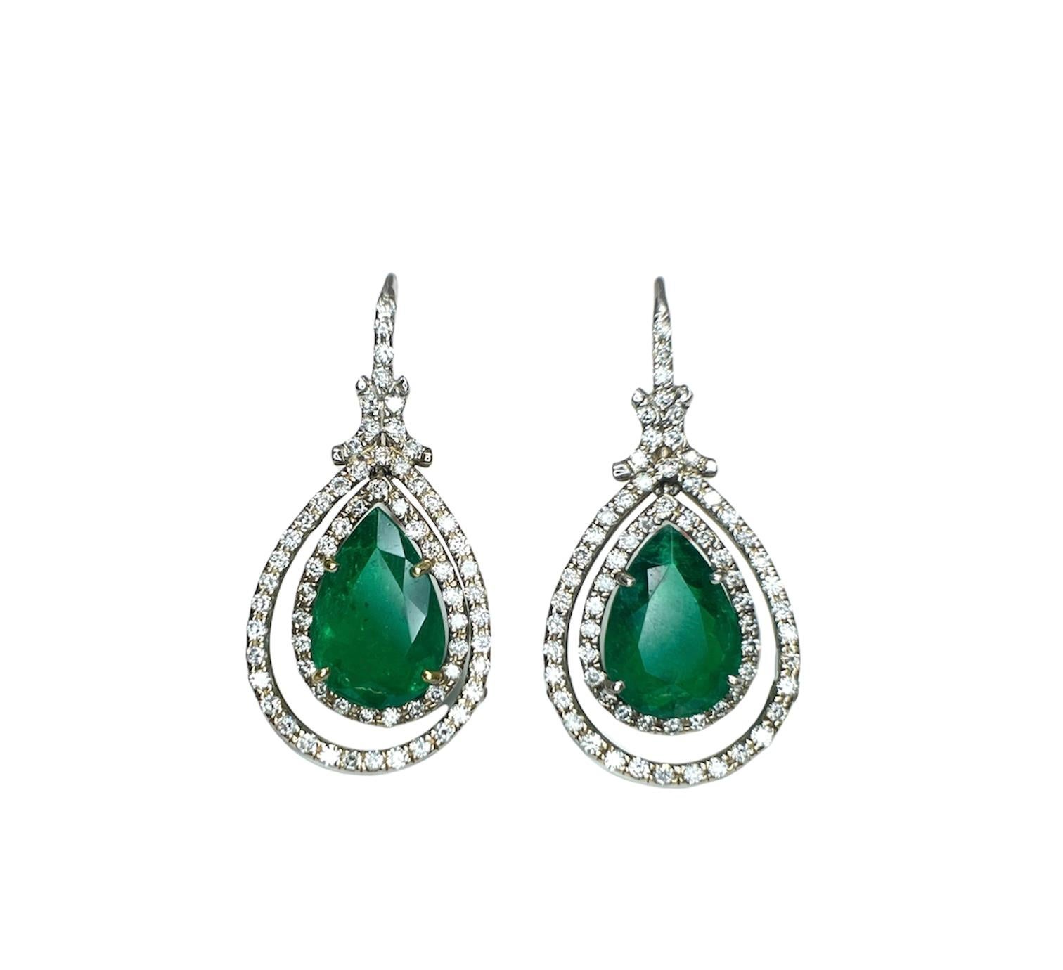 Stunning hand-made double halo pear shape emerald earrings. The earrings feature two natural pear shape emeralds weighing a total of 4.25 ct. The earrings also have round brilliant cut diamonds surrounding the pear shapes weighing 1.30 ct and graded