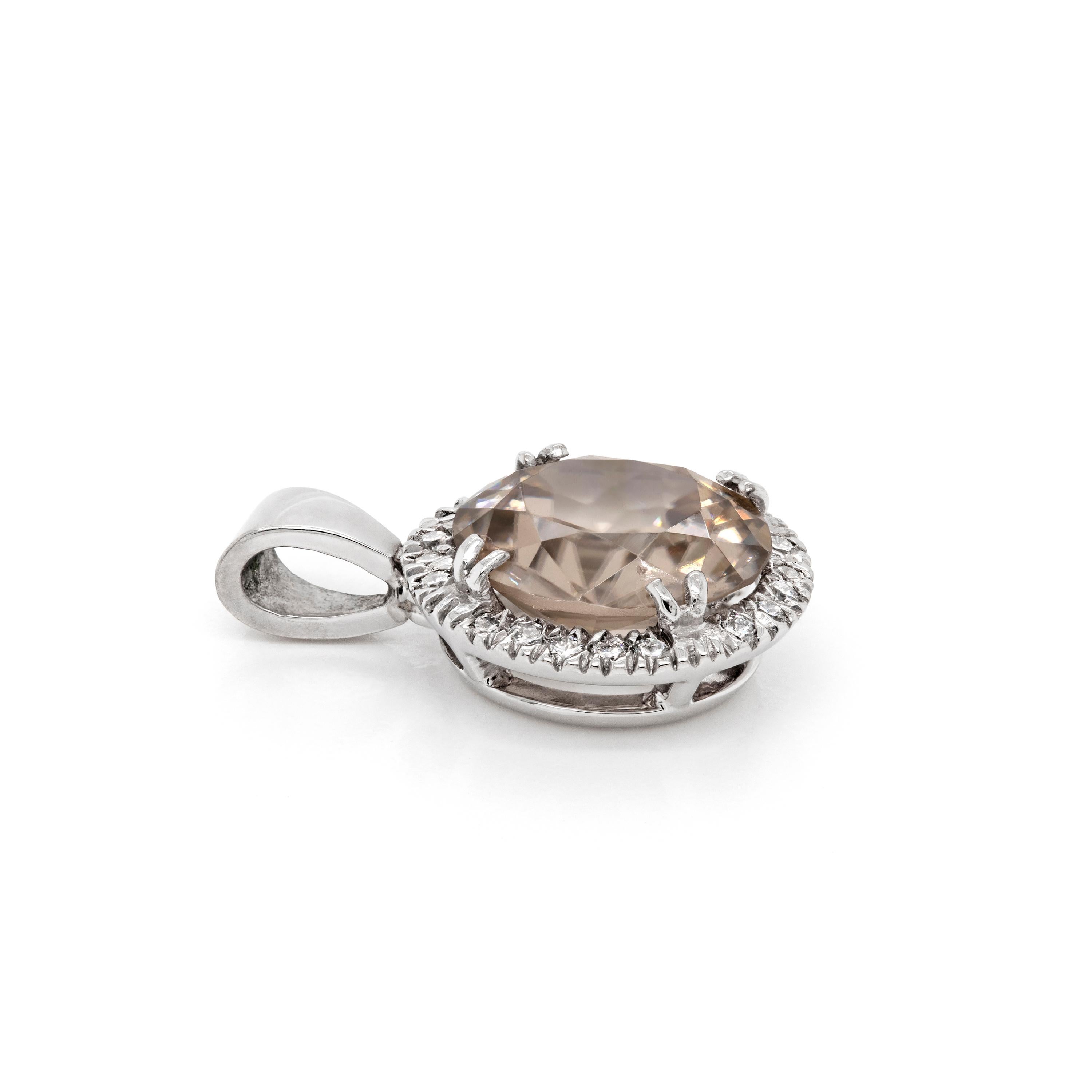This beautiful piece features a cushion shaped Zircon weighing 4.25ct mounted in a four claw, open back setting. The gemstone is beautifully surrounded by a halo of 20 round brilliant cut diamonds weighing a total of 0.20ct all mounted in platinum.