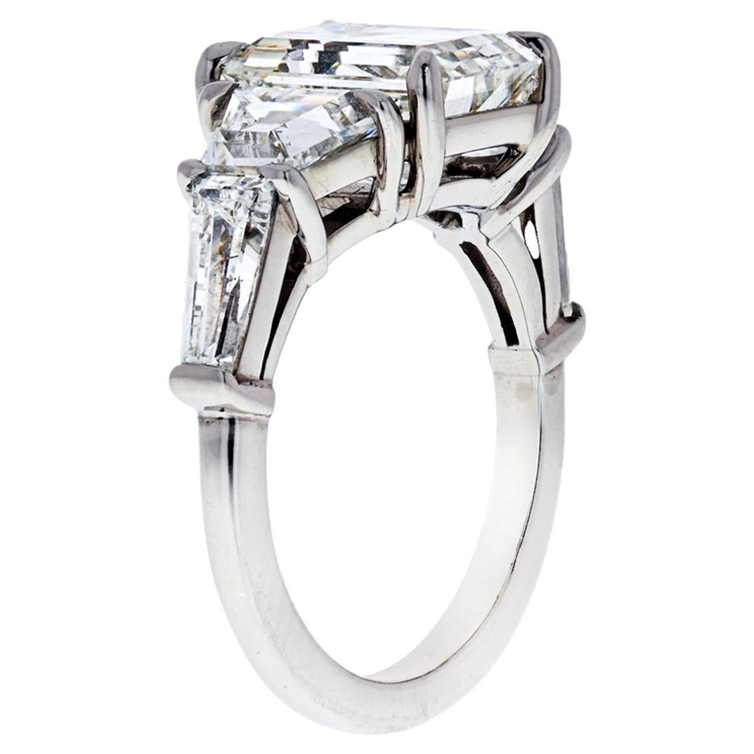 This is a new spin on a classic three stone emerald cut and tapered baguette engagement ring. This beauty is made with 5 diamonds instead of three: center stone emerald cut, two trapezoids, and two tapered baguettes. 

What are trapezoids?