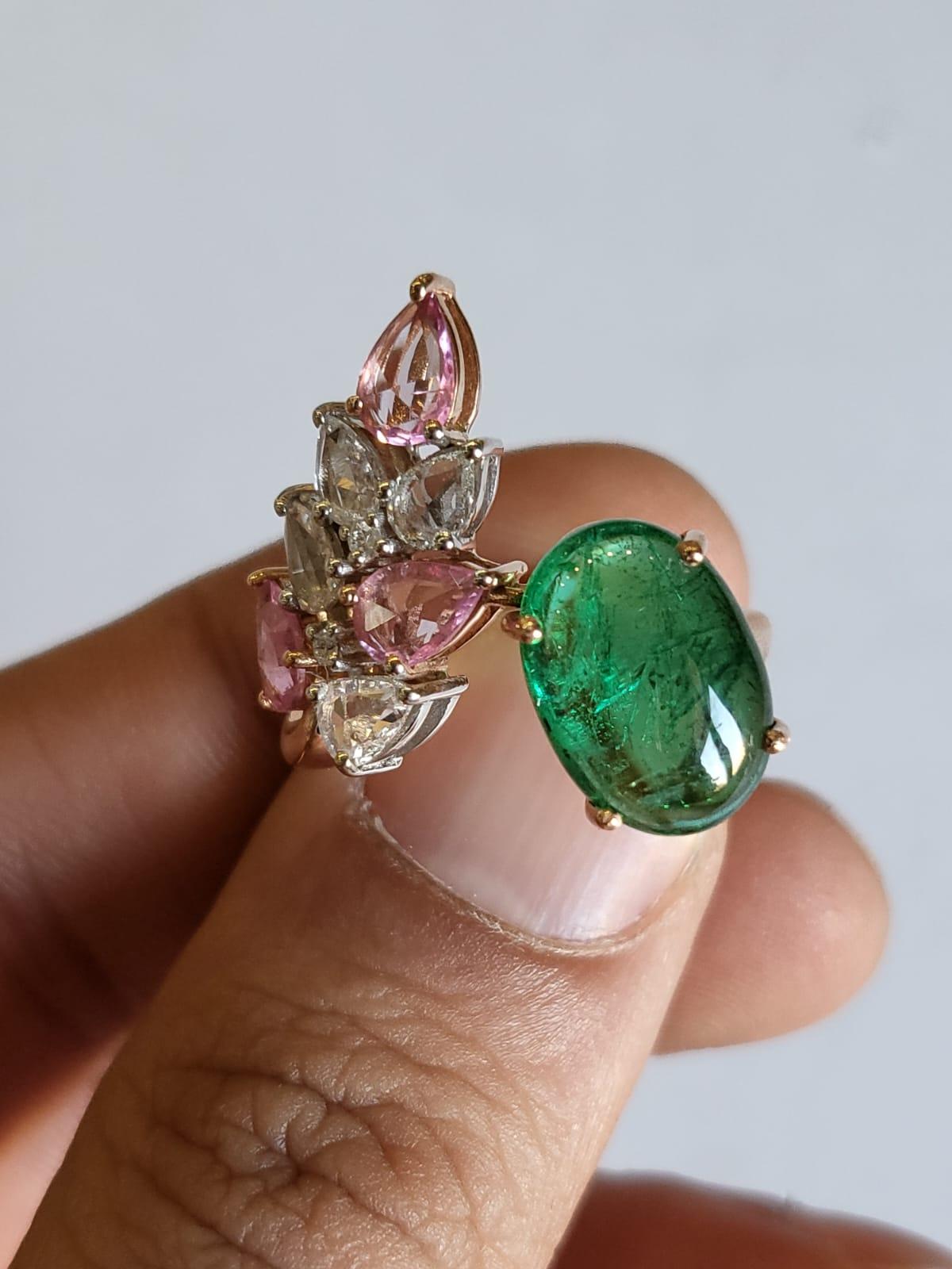 A very gorgeous and one of a kind, Emerald & Pink Sapphire Cocktail Ring set in 18K Rose Gold & Diamonds. The weight of the Emerald cabochon is 4.27 carats. The Emerald is completely natural, without any treatment and is of Zambian origin. The