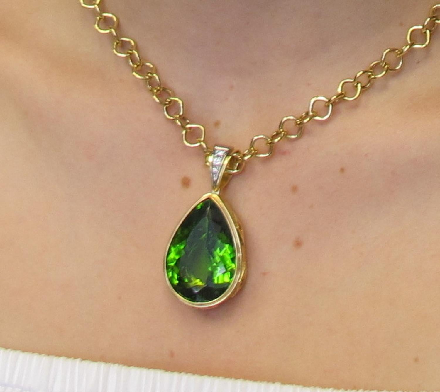This exquisite pendant will demand attention whenever it's worn! It is comprised of a pear shaped peridot measuring 20x30mm and weighing 42.90 carats, set with 5 round yellow sapphires (0.89 carats total weight), and 3 round brilliant cut diamonds