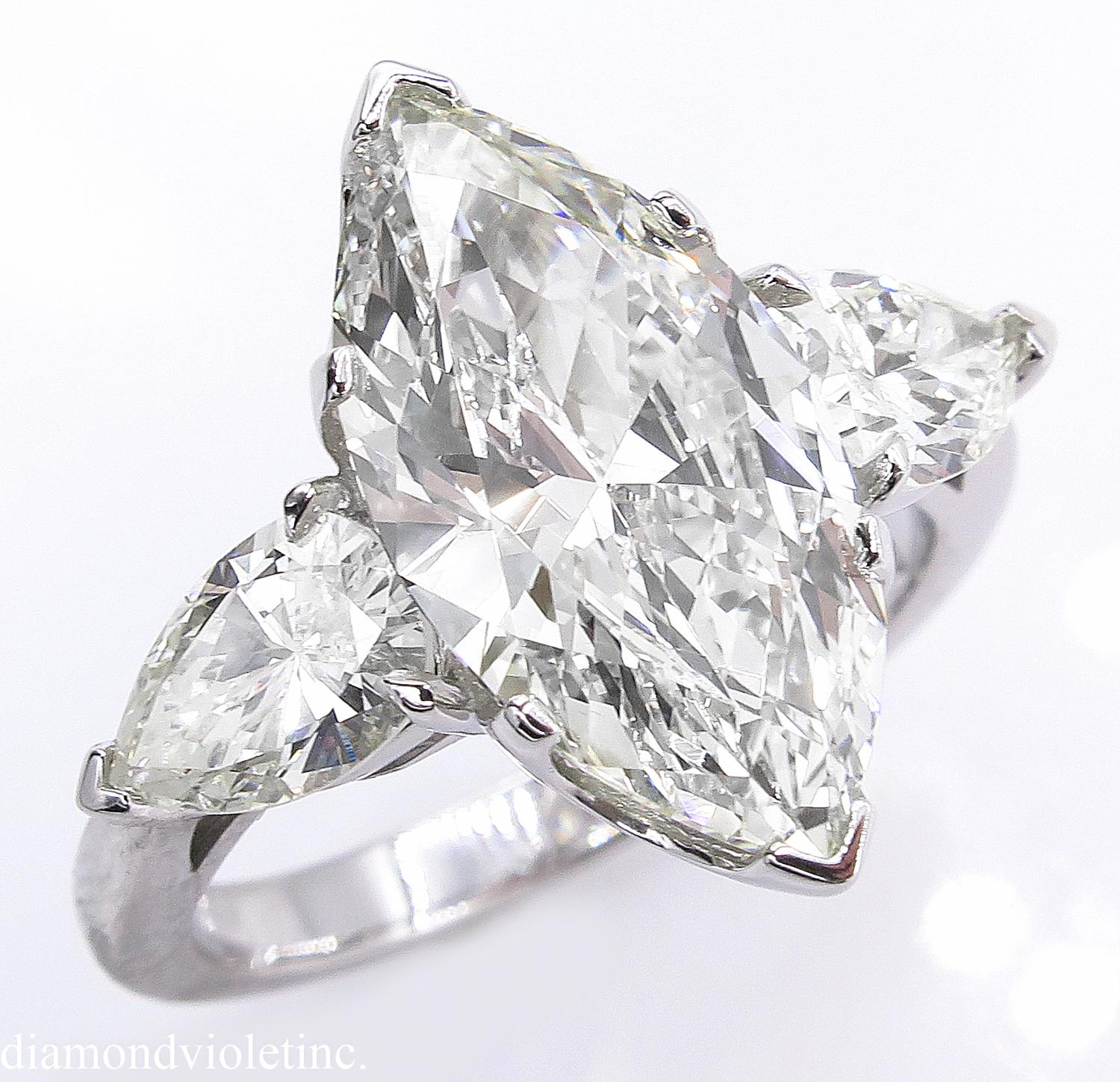 A Breathtaking Estate HANDMADE PLATINUM (stamped) Marquise Diamond Three-Stone Engagement ring. The Prong Set Marquise Shaped Center Diamond is GEMOLOGIC appraised as 3.29CT with measurements of 15.70x8.06x4.40mm in J-K color SI1 clarity.
It is set