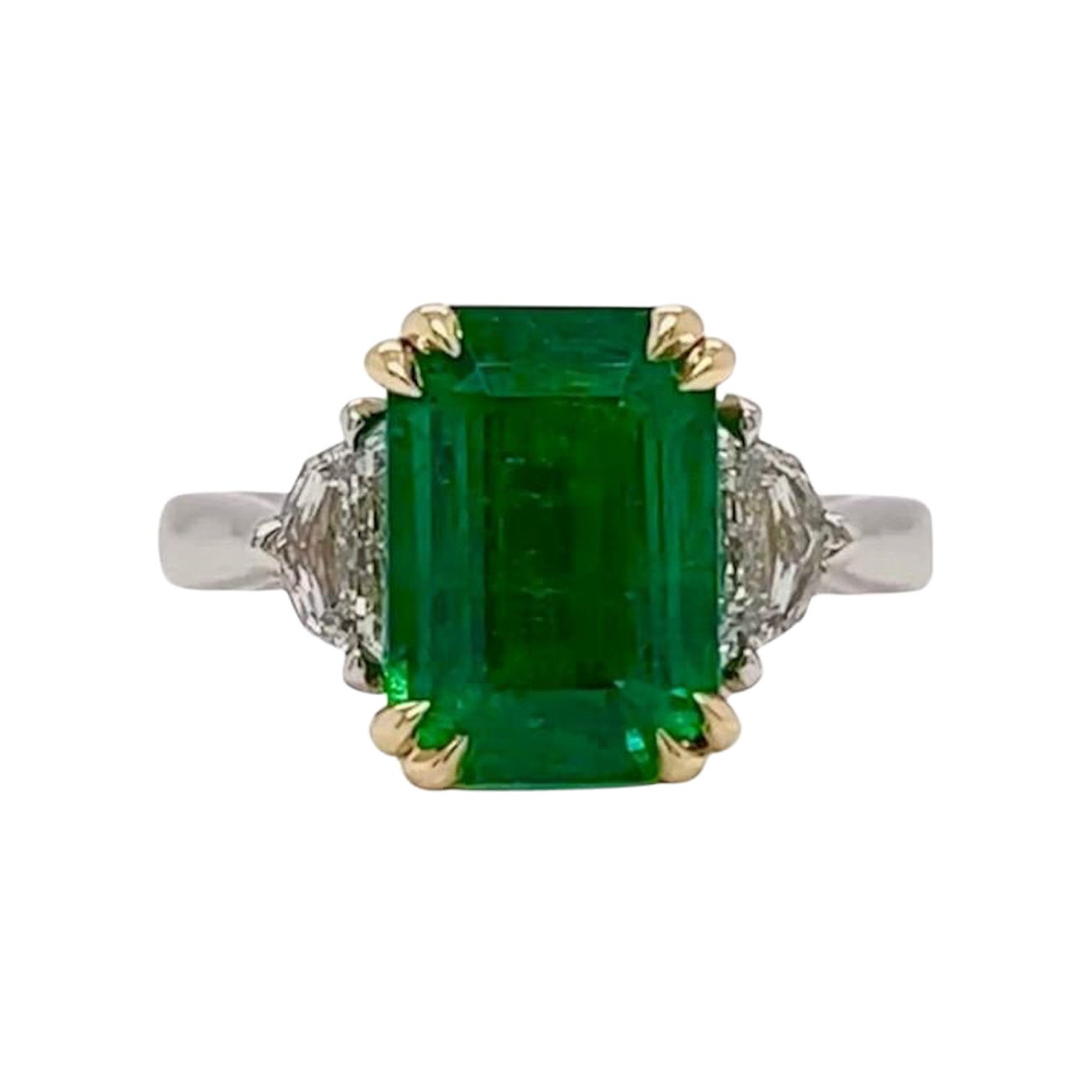 4.29ct herrlichen feinen lebendigen grünen Smaragd mit einer eleganten länglichen Proportion & 0.53ctw F/G VS Epaulette geformten Seitensteinen. 

Eingefasst in eine fachmännisch gefertigte Platin & 18K Gelb Comfort fit Fassung. 

Ring Größe 6.5