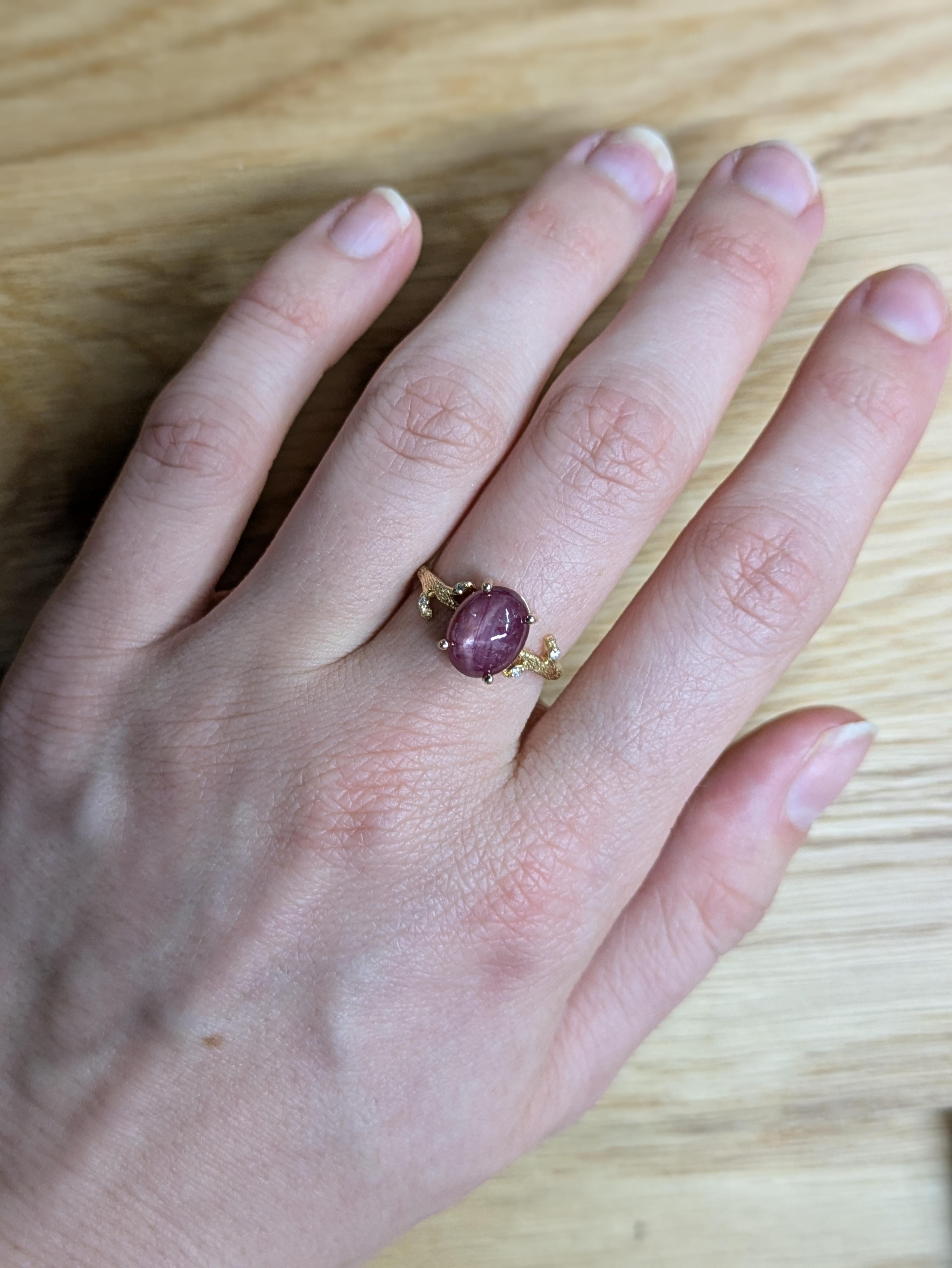 This statement natural inspired ring showcases a stunning 4.23 carat oval Star Ruby gemstone, with natural earth mined diamonds on each side. The setting is crafted in a solid 14K gold textured band, exuding a bold and luxurious charm. This Star