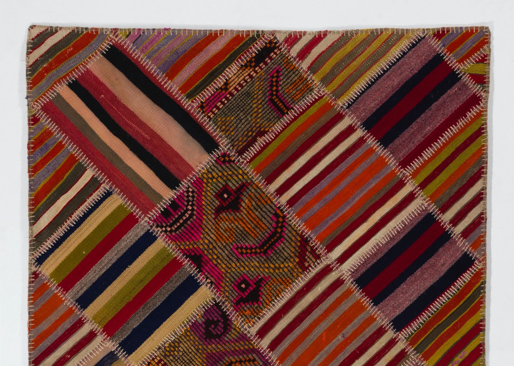 A colorful Turkish kilim rug (flat-weave) hand-stitched from pieces of hand-woven vintage kilims. It features an assortment of patches in vivid colors with a design of stripes and hook motifs. It is made of natural wool, very sturdy, professionally