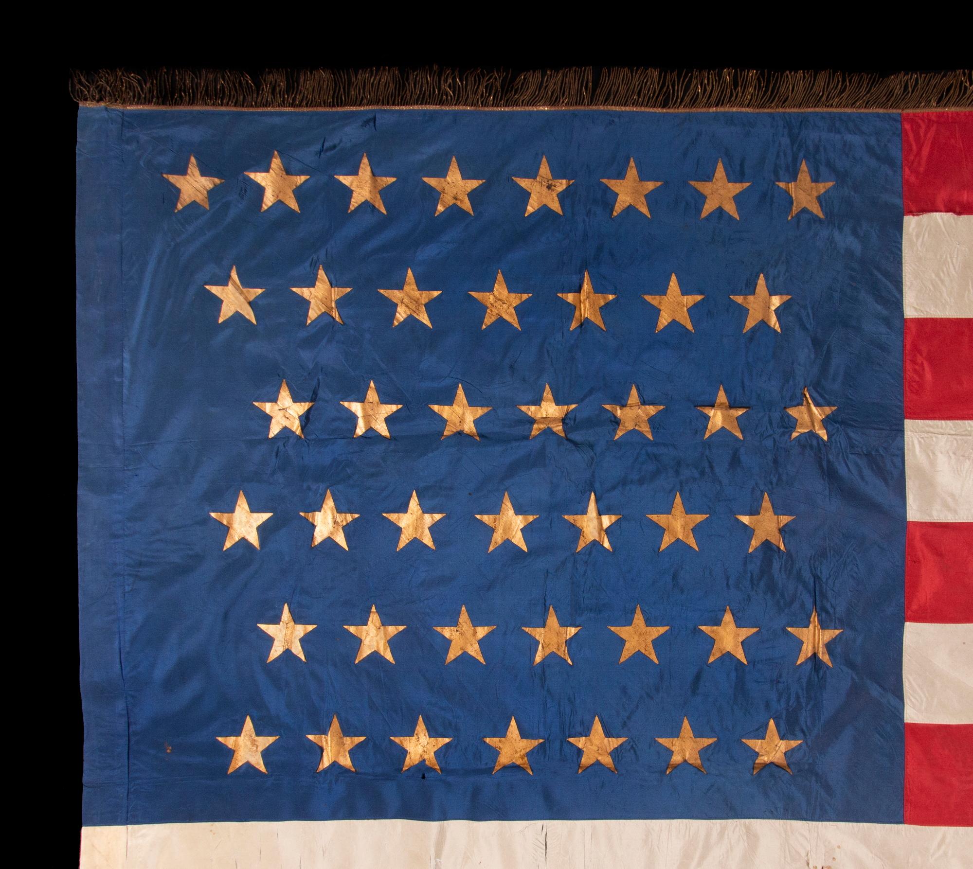 43 GILT-PAINTED STARS ON A SILK, ANTIQUE AMERICAN FLAG WITH BULLION FRINGE; REFLECTS THE ADDITION OF IDAHO AS THE 43RD STATE ON JULY 3RD, 1890, ONE OF THE RAREST STAR COUNTS AMONG SURVIVING AMERICAN FLAGS OF THE 19TH CENTURY

Numerous flags appeared
