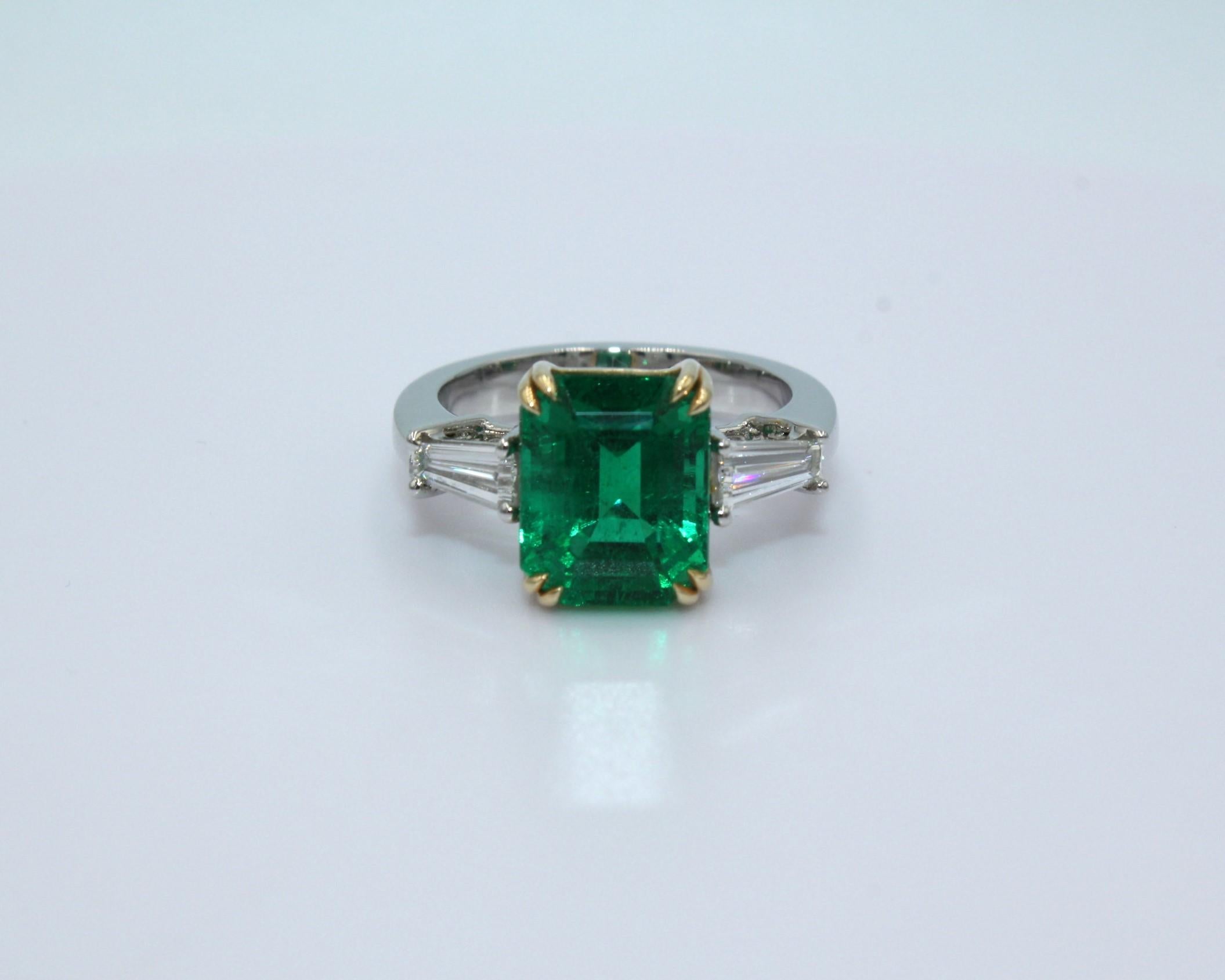 Three-Stone Ring with 4.30 carats Emerald Cut Zambian Emerald and two Tapered Baguette diamonds, totaling diamond weight of 0.58 carat on the side. 

This stunning Emerald Diamond Ring will highlight your elegance and uniqueness. 

Item Details:
-