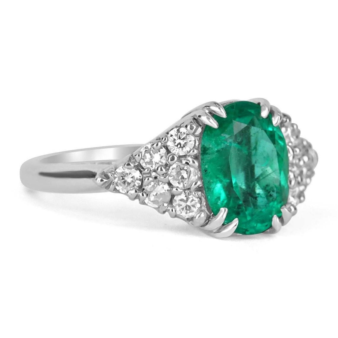 Cette magnifique bague à émeraudes et diamants de Colombie est exposée dans toute sa splendeur. La pierre centrale pèse près de quatre carats et présente une belle couleur vert vif et un excellent/très bon lustre. L'émeraude présente des taches de