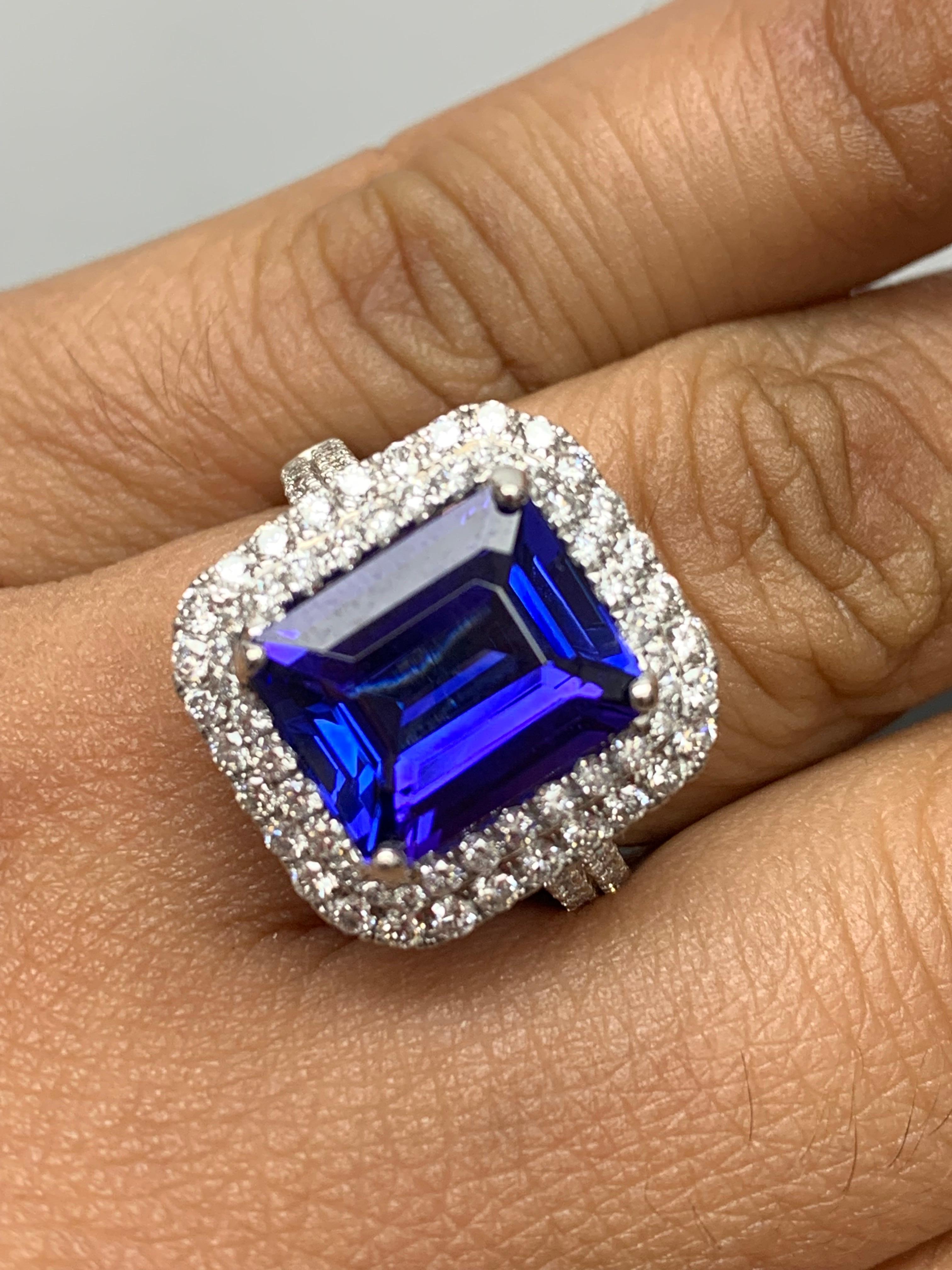 A stunning ring showcasing a brilliant color Tanzanite weighing 5.76 carats surrounded by a row of diamonds. Flanking the center stone are two rows of brilliant cut 84-round diamonds, weighing 1.47 carats total, Made in 18k White Gold.