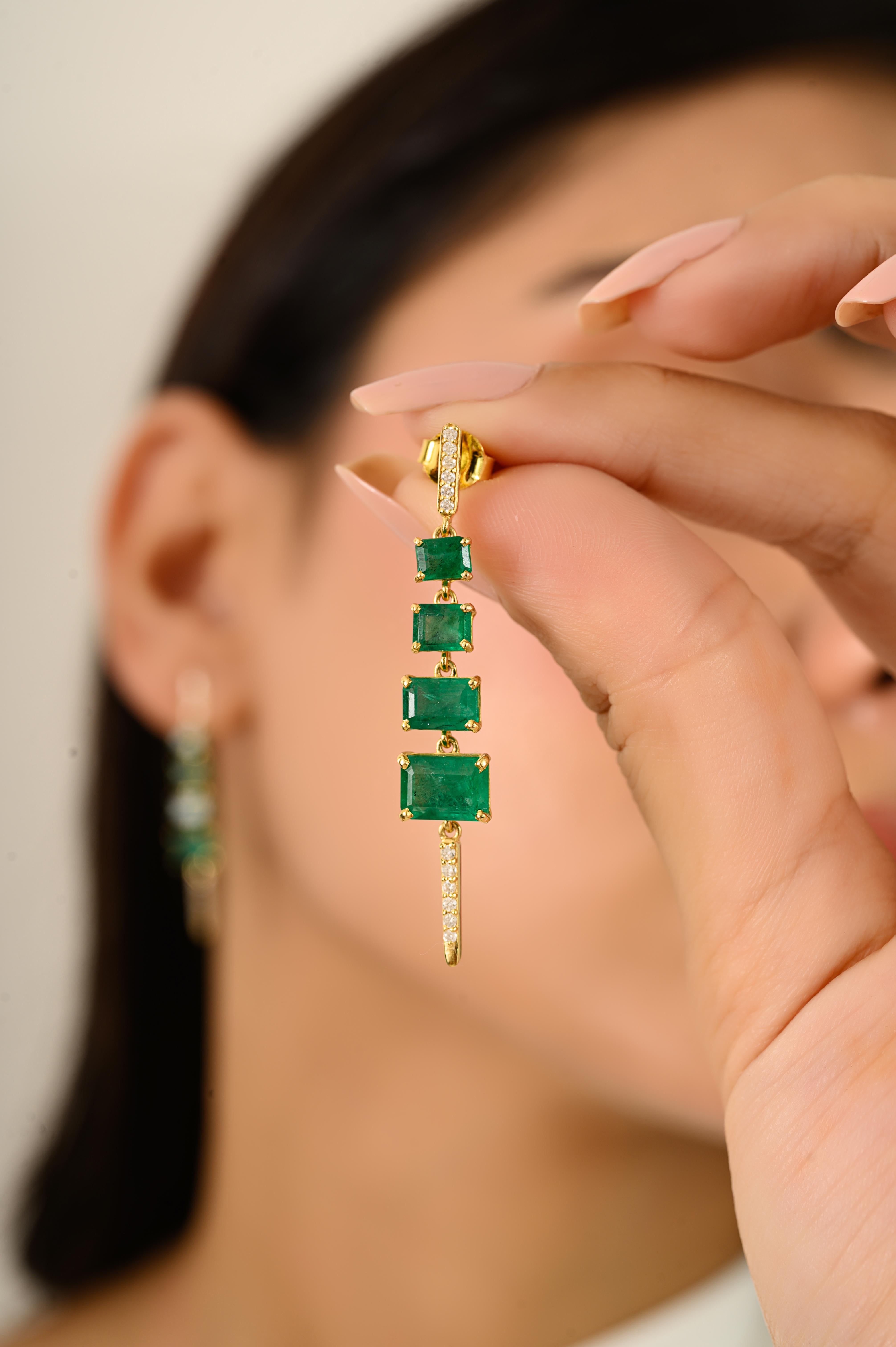 Questi moderni orecchini pendenti presentano 4,32 carati di smeraldi naturali dello Zambia con tagli smeraldo graduati, abbinati a 0,16 carati di diamanti tondi brillanti. Le pietre sono incastonate e pavoneggiate in oro giallo 14k, creando un