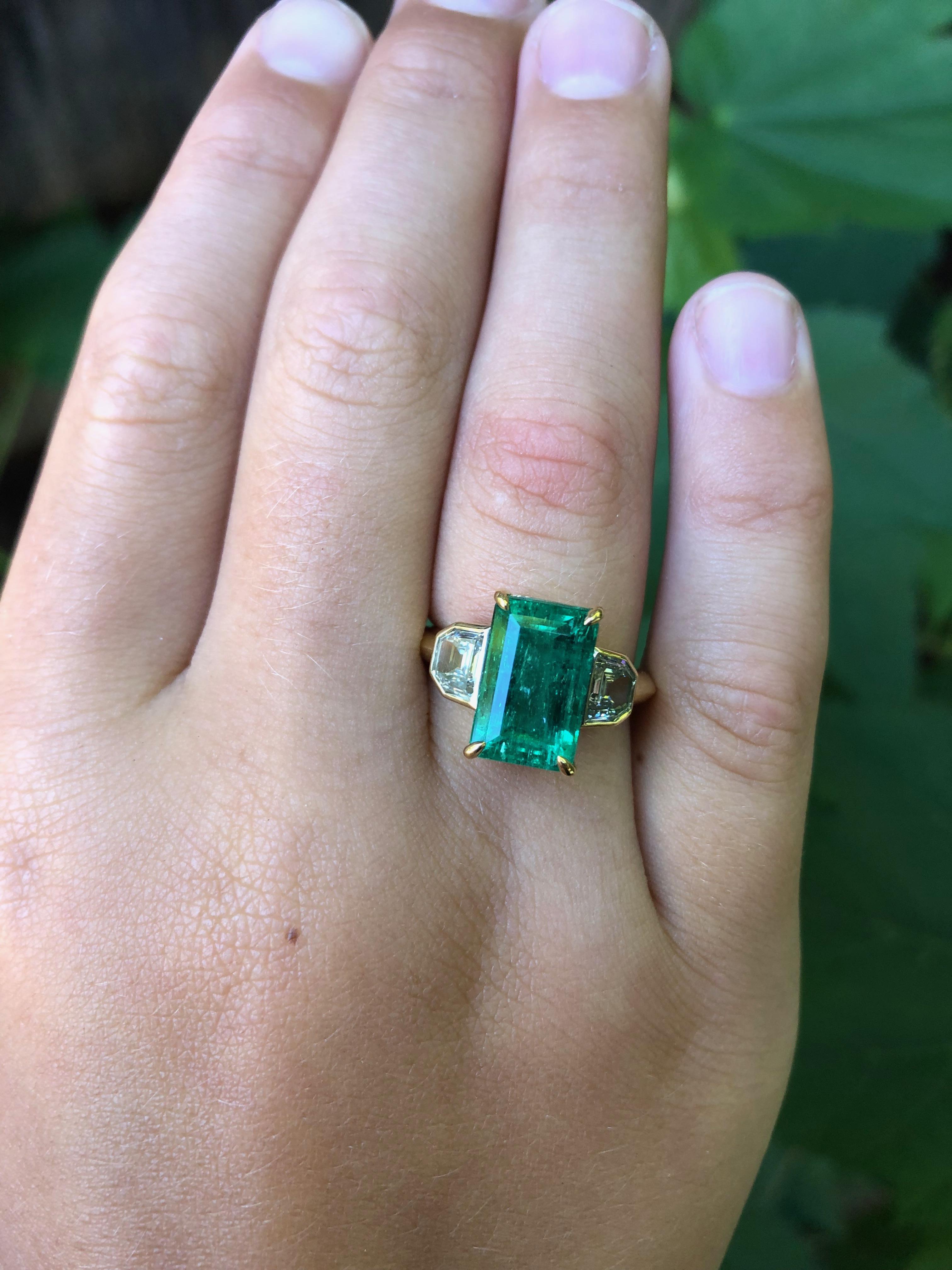 4.35 carat emerald cut Colombian Muzo Emerald is set in a hand fabricated 18 karat gold setting with 0.94 carat total weight true antique VS-KL diamonds. This emerald is vibrant with an alpine green color, and certified 